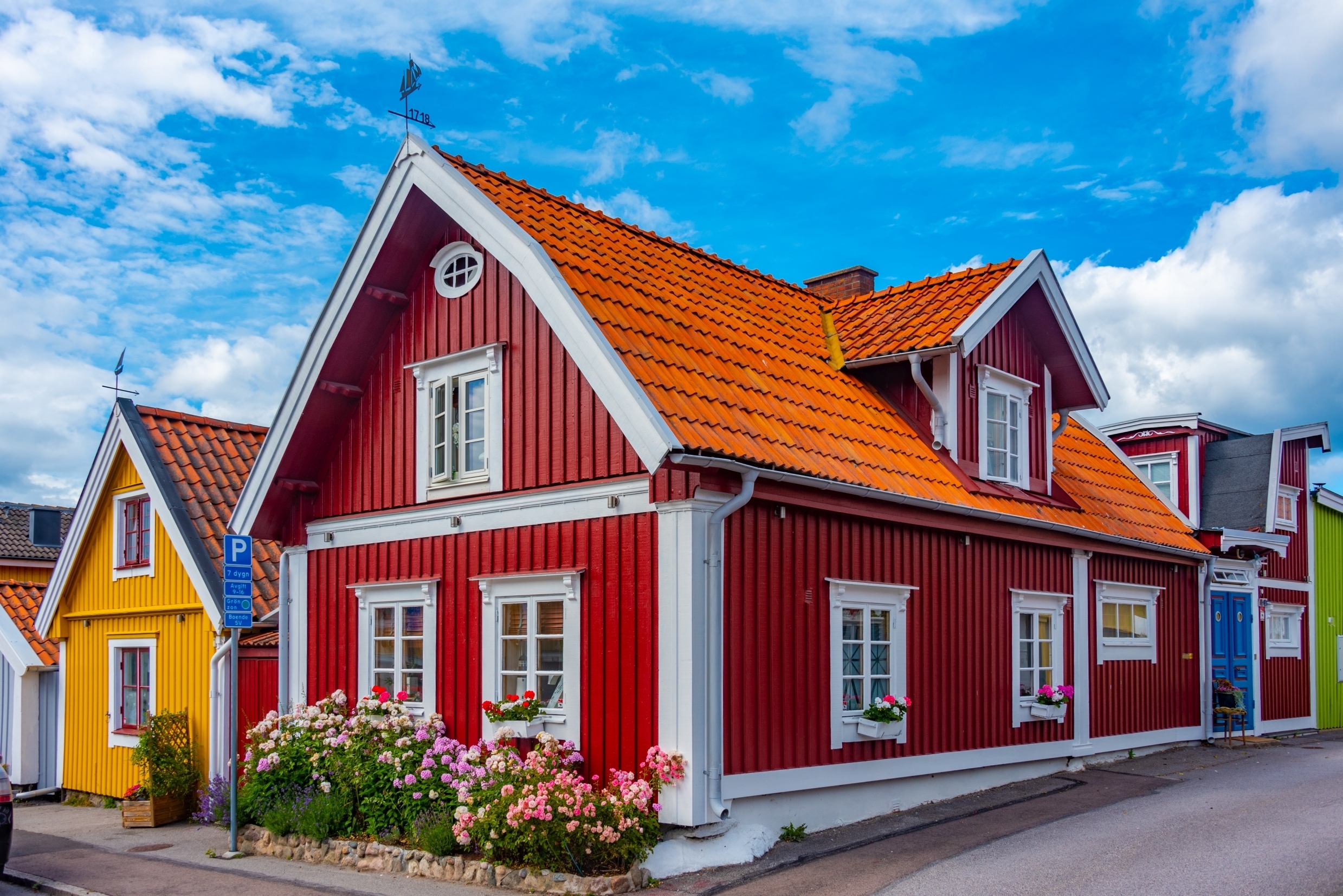 Traditionelle og stemningsfulde træhuse i Karlskrona, Sverige, med farverige facader og blomsterdekorationer på en solrig sommerdag