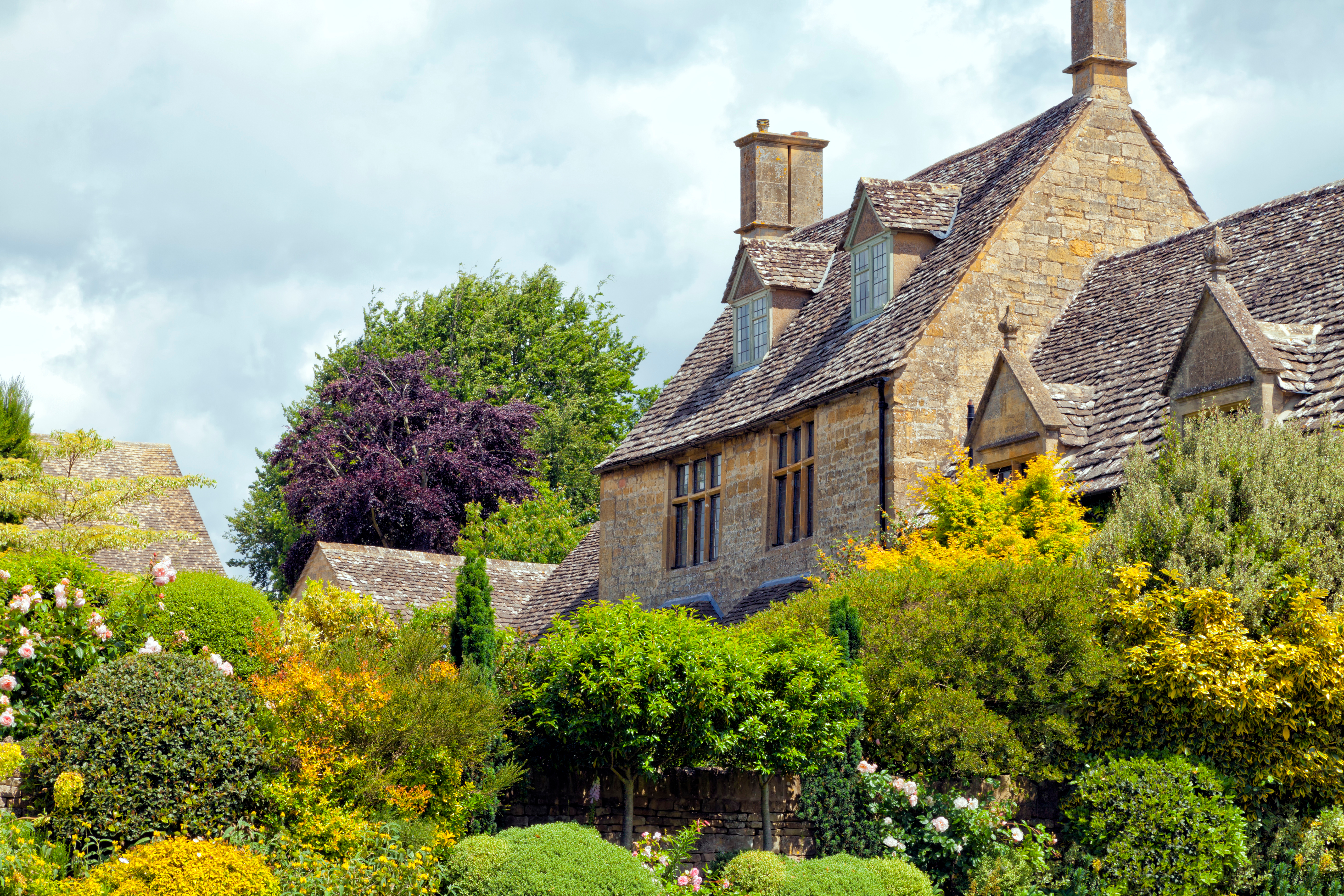 Traditionelt engelsk hus i Cotswolds med frodig sommerhave og skifertag