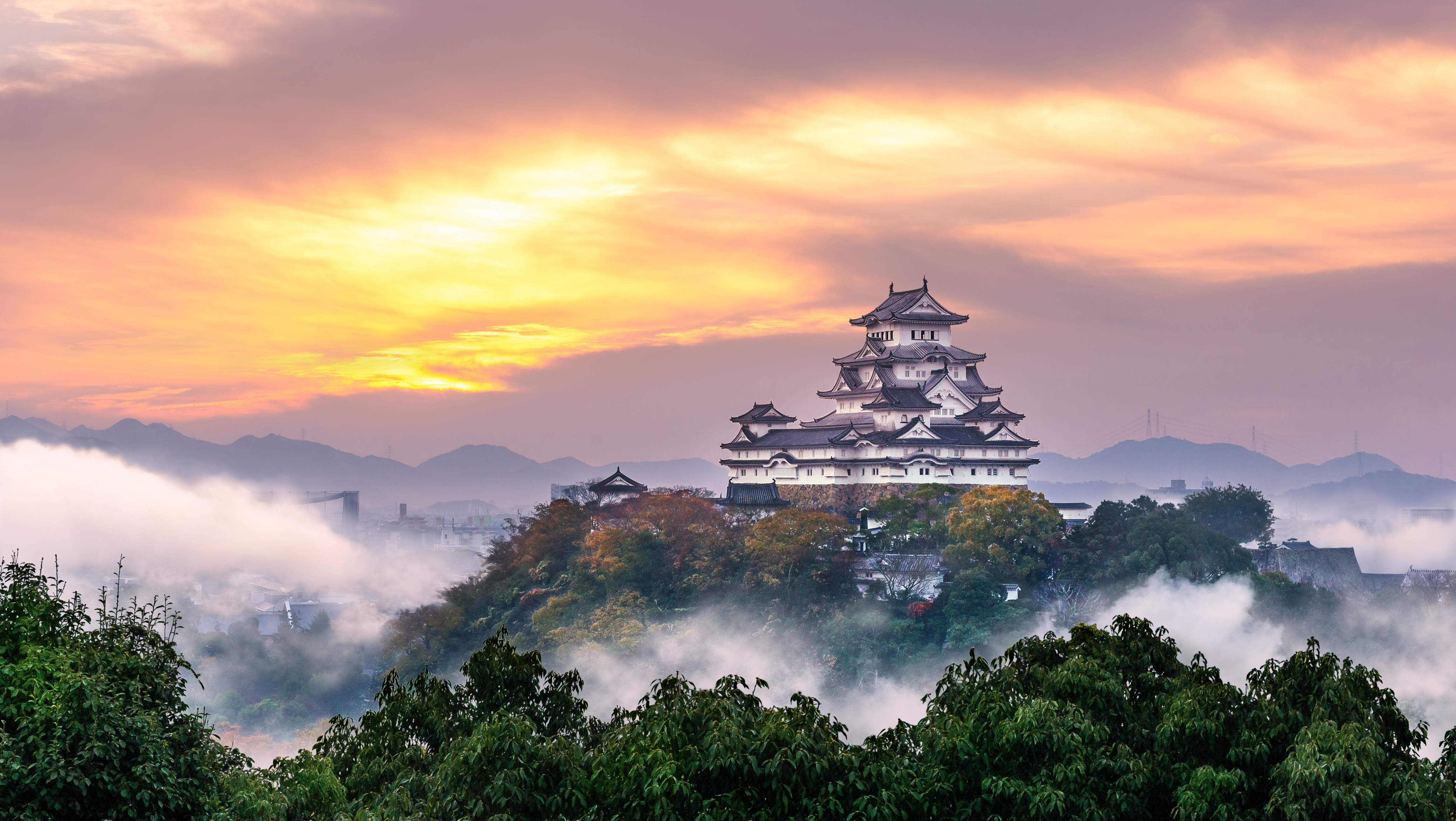 Smukt japansk slot i traditionel arkitektur omgivet af tåge ved solnedgang