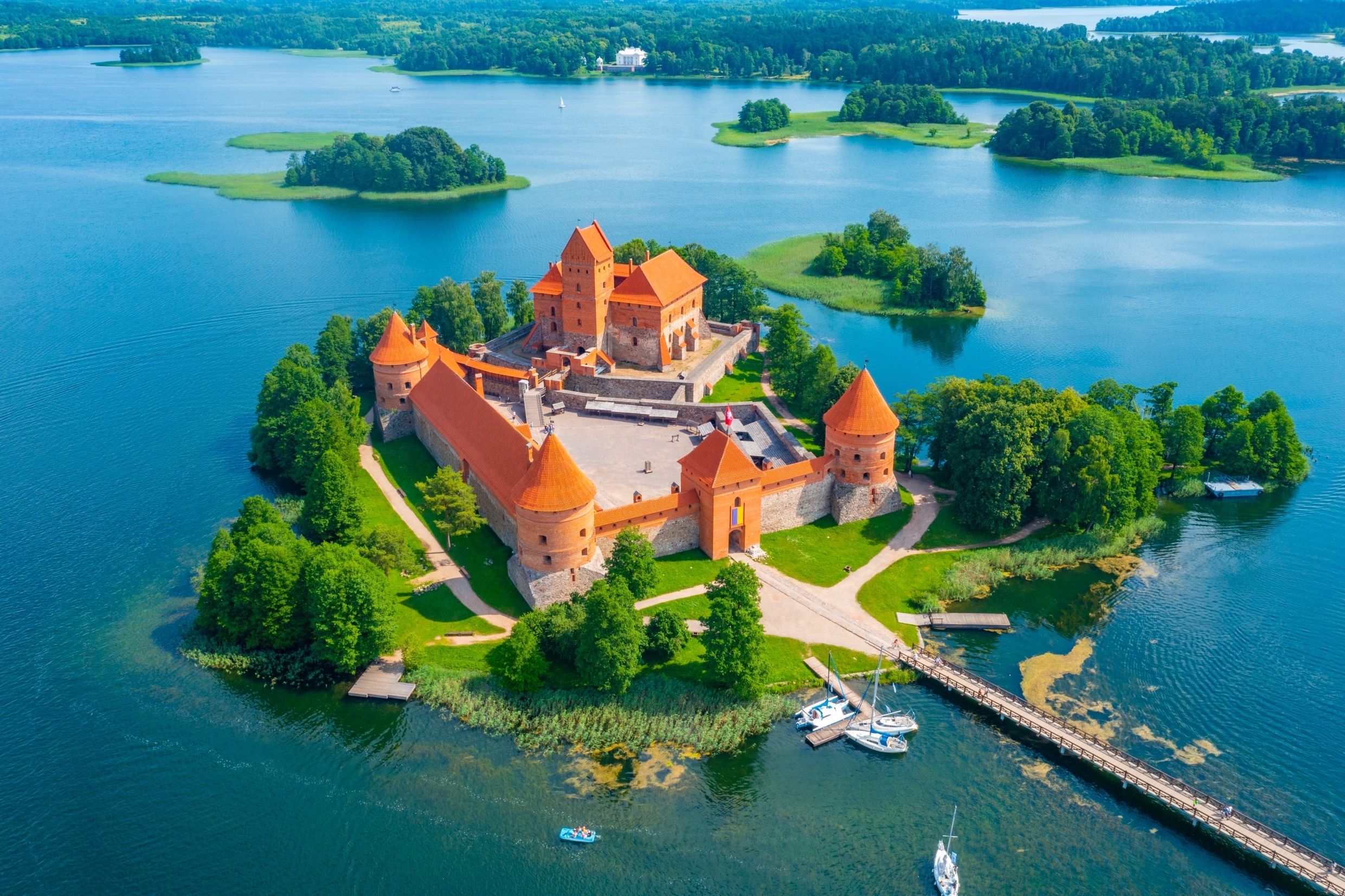 Sommerudsigt over Trakai-fæstningen i Litauen - et malerisk ø-slot fra middelalderen med røde mure og tårne omgivet af Galve-søens klare vand