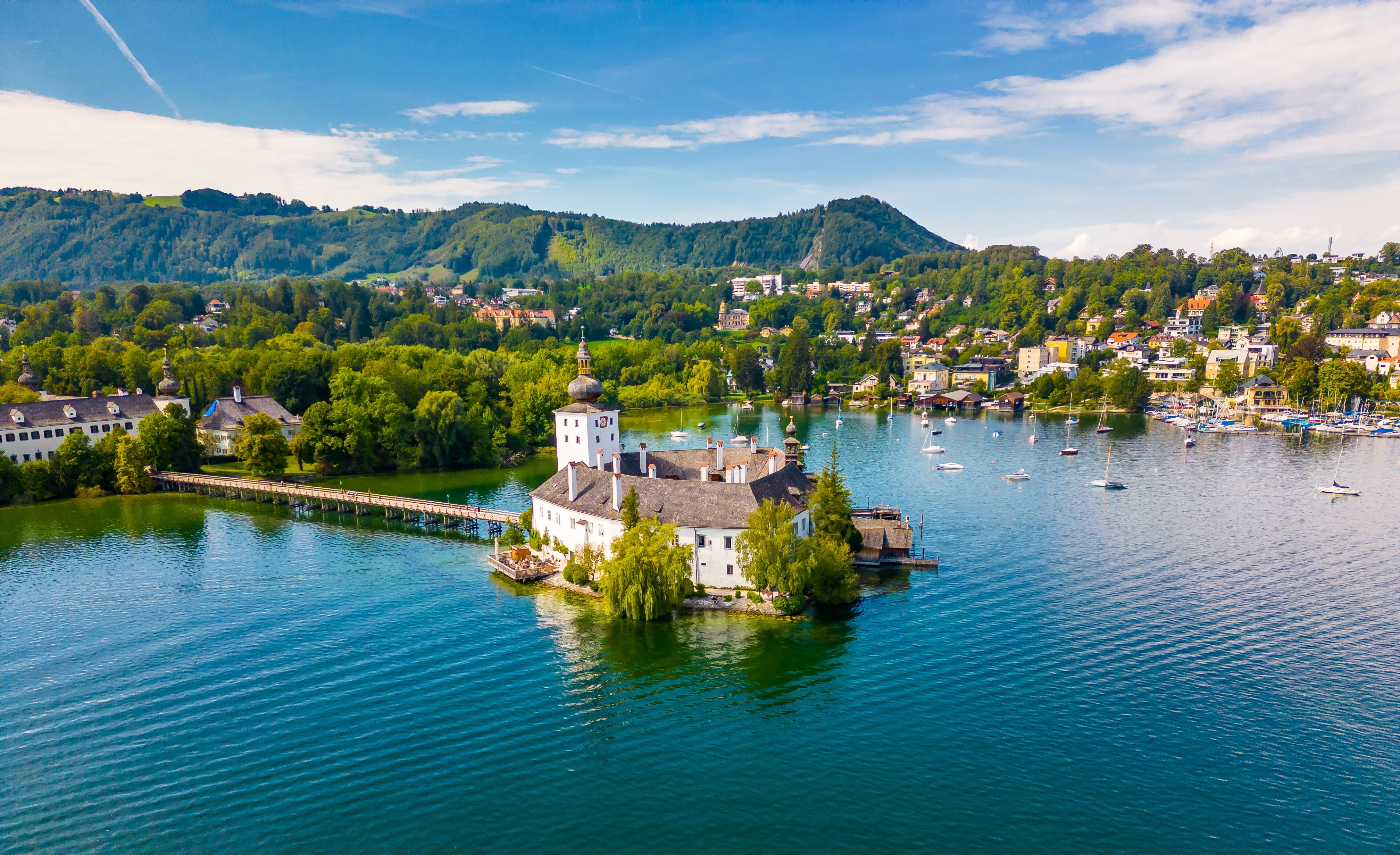Smukt luftfoto af Schloss Ort-slottet på Traunsee-søen i Gmunden, Østrig, med turkisblåt vand og grønne alper