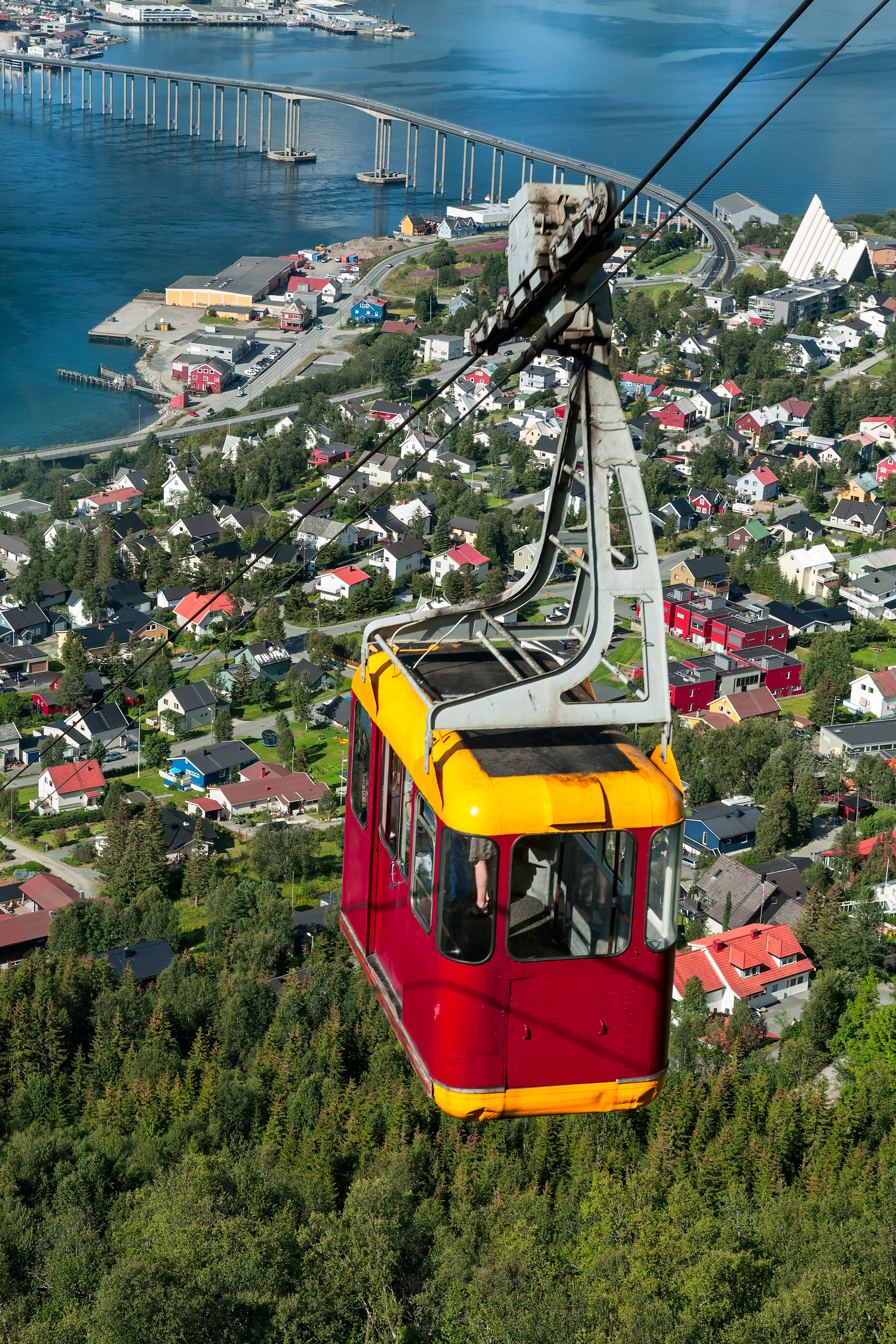Rød kabelbil over Tromsø med udsigt over den arktiske katedral og den lange bro over fjorden i det nordlige Norge