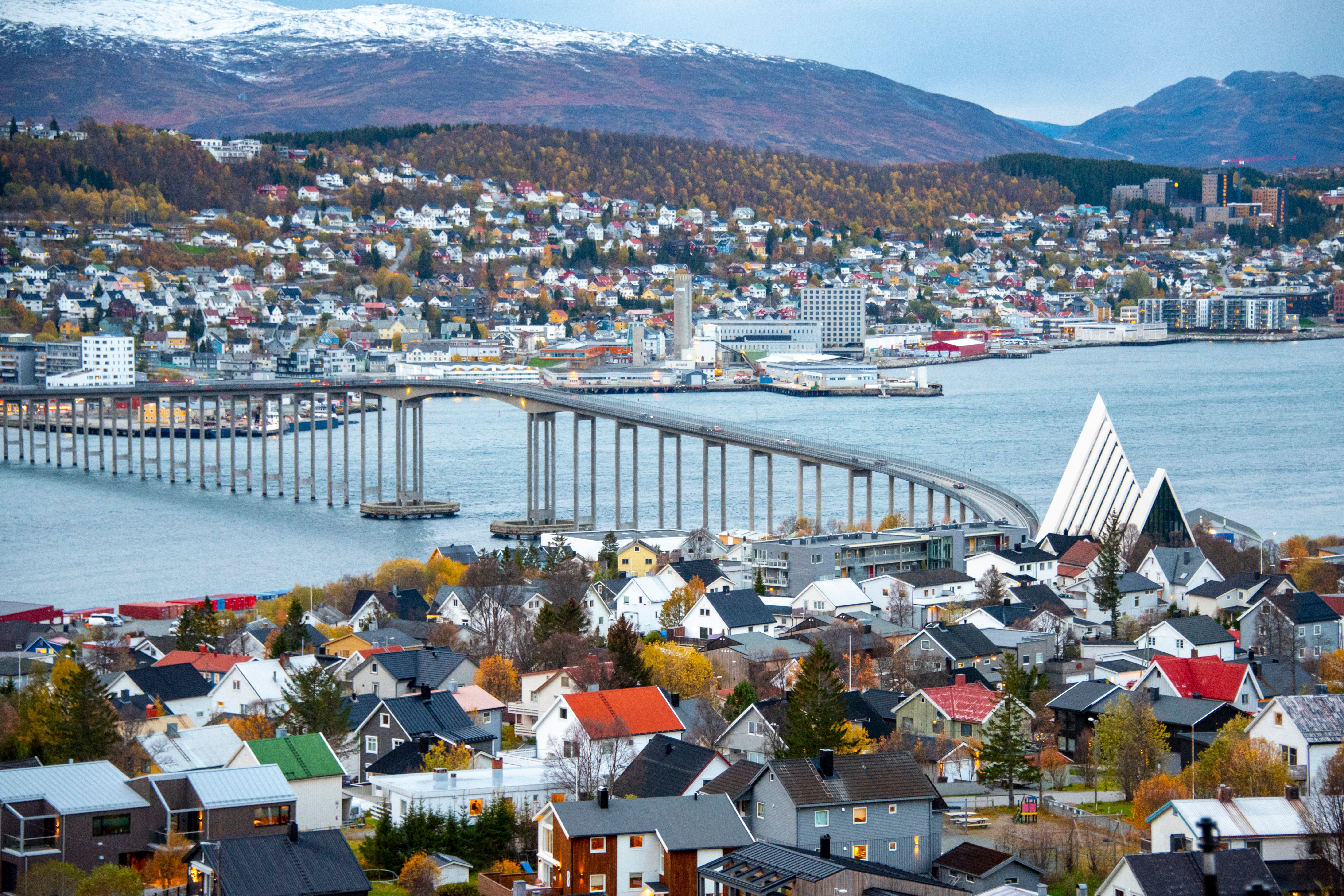 Luftudsigt over Tromsø i Norge med den hvide Arktiske Katedral og bro der krydser fjorden med sne på bjergene