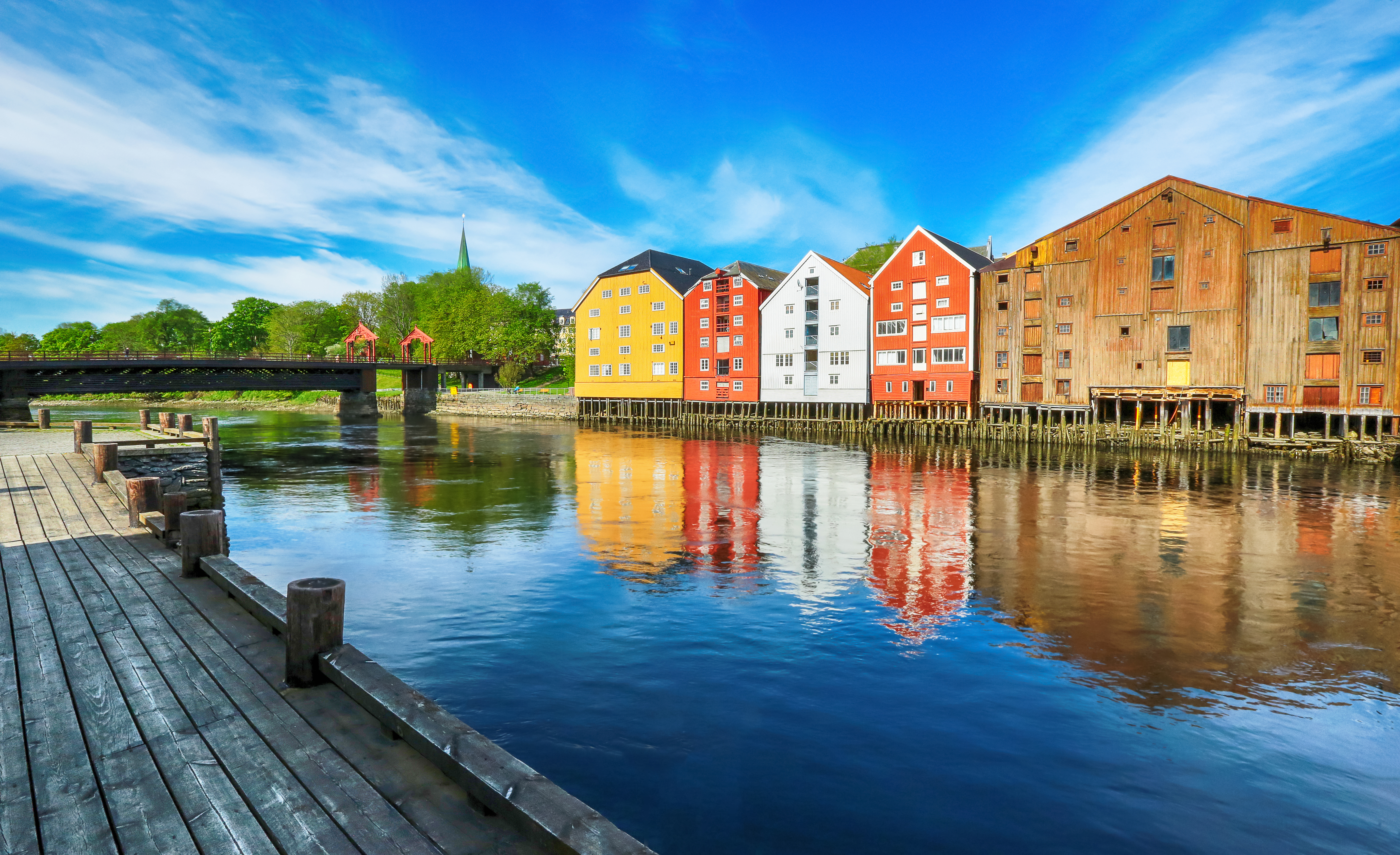 Stemningsfuldt vue over Trondheims historiske centrum med de karakteristiske træbygninger langs Nidelva-floden, den historiske Gamle Bybro og Nidaros-katedralen