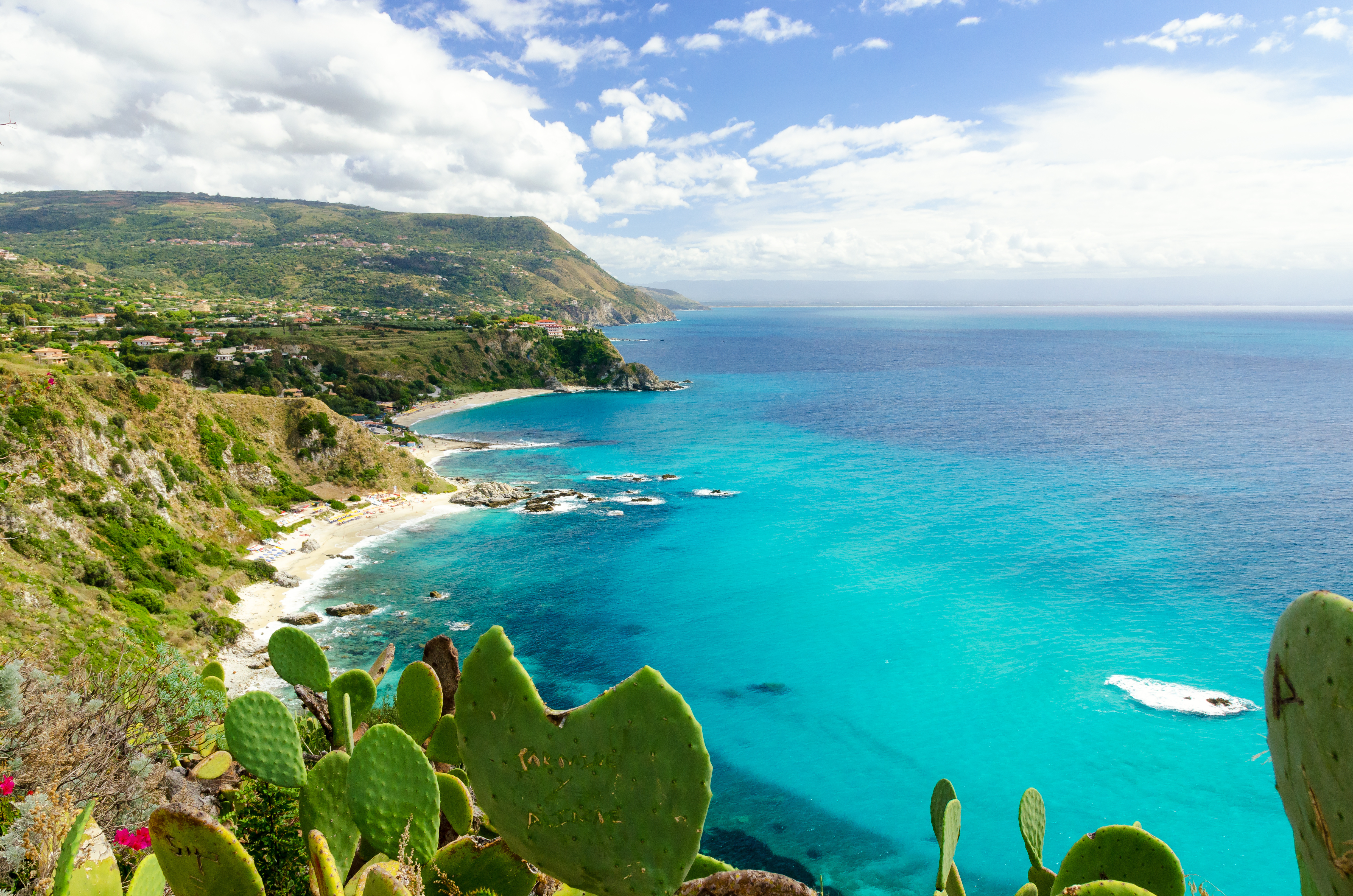 Pragtfuld udsigt over det turkise hav ved Capo Vaticano nær Tropea i Calabrien, Italien, med kaktusplanter i forgrunden og klart blåt Middelhav i baggrunden