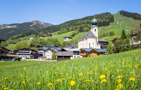 Charmerende Tyrolean landsby med kirke omgivet af grønne alper og vandresti