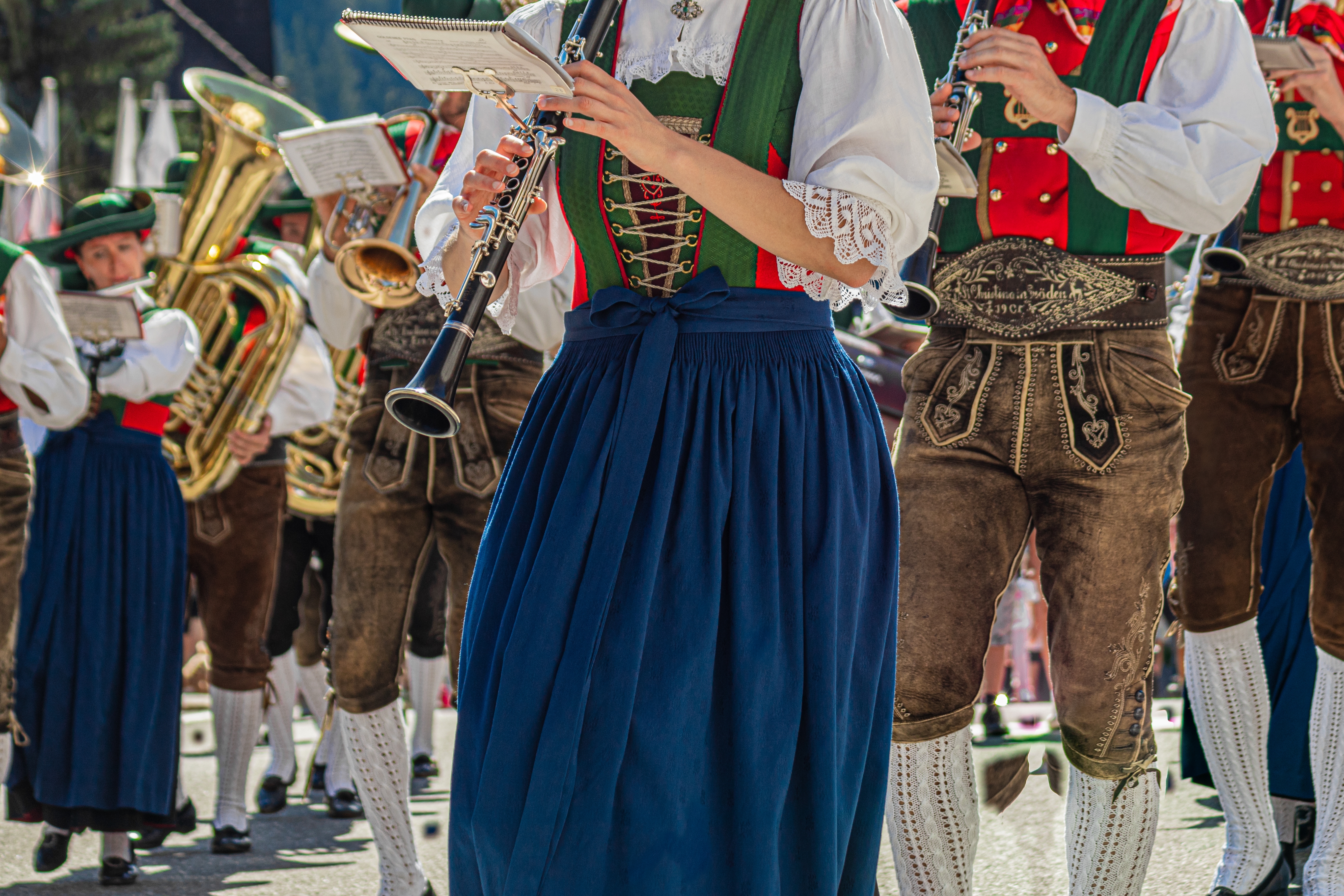 Musikere i traditionelle tyroleske dragter spiller klarinet og messinginstrumenter ved en festlig parade i Val Gardena, Italien
