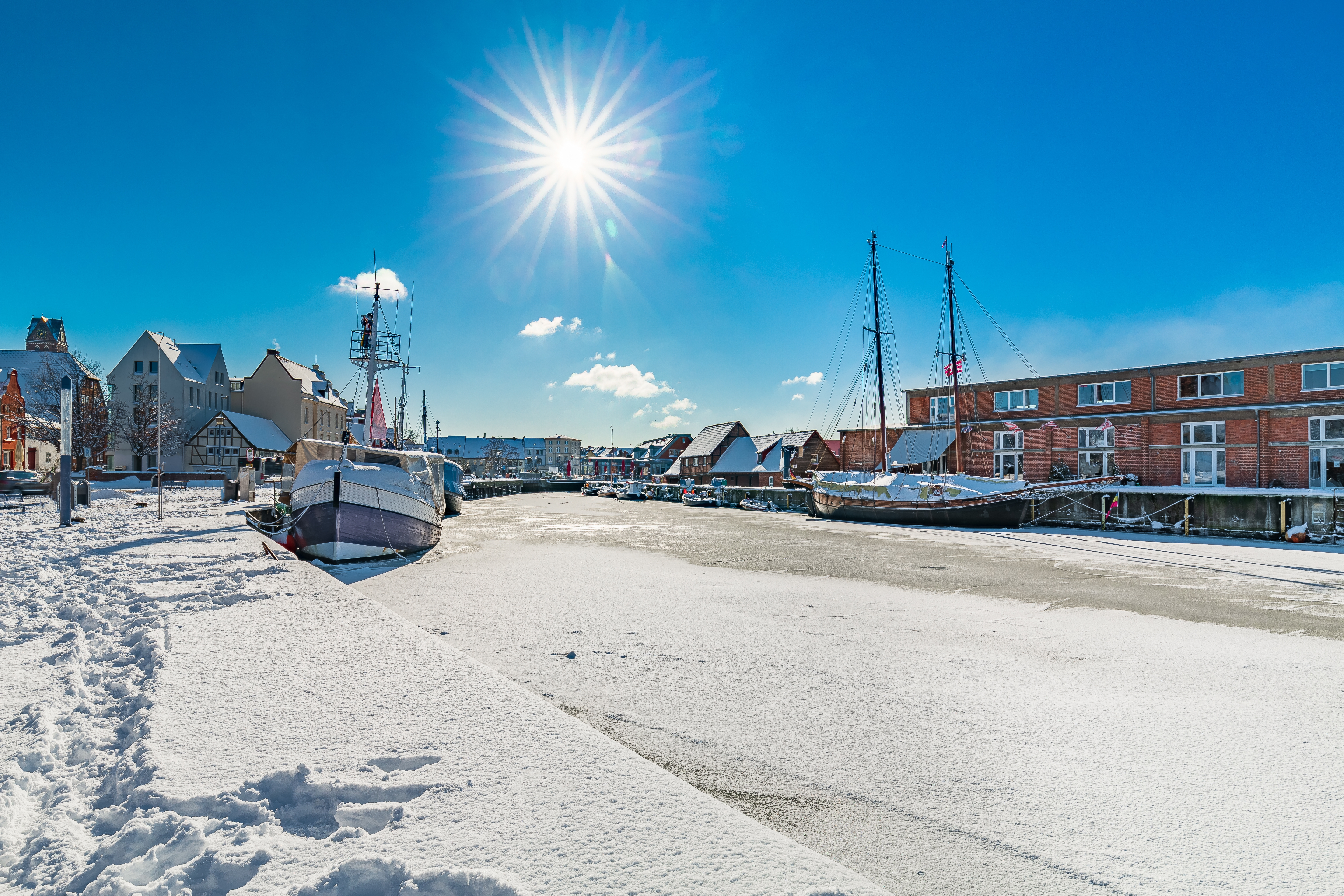 Smuk vinterhavn i Wismar, Tyskland med både og sne under klar blå himmel