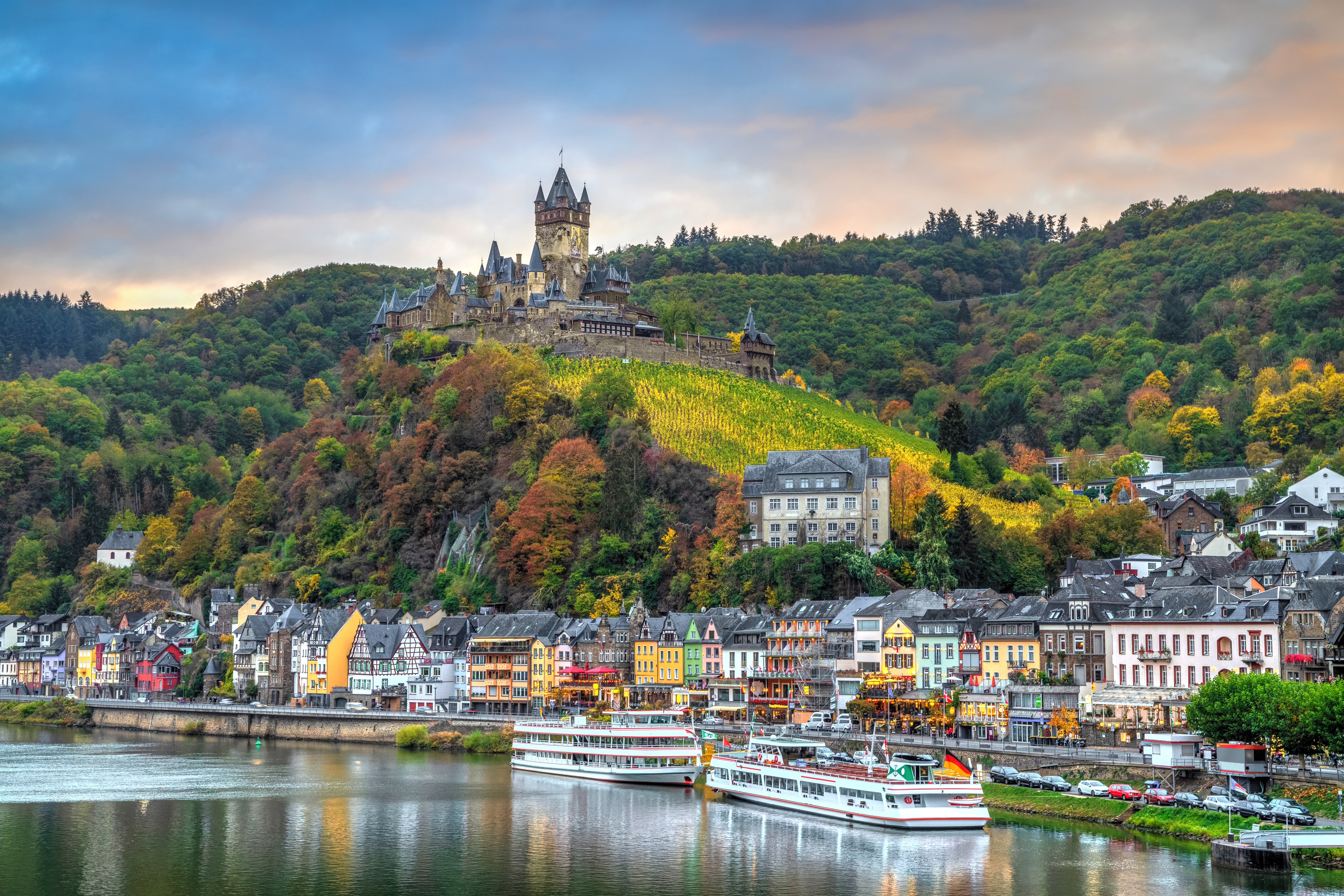 Malerisk Cochem med slot på bakke, efteraars vinmarker og farverige huse langs Rhinen