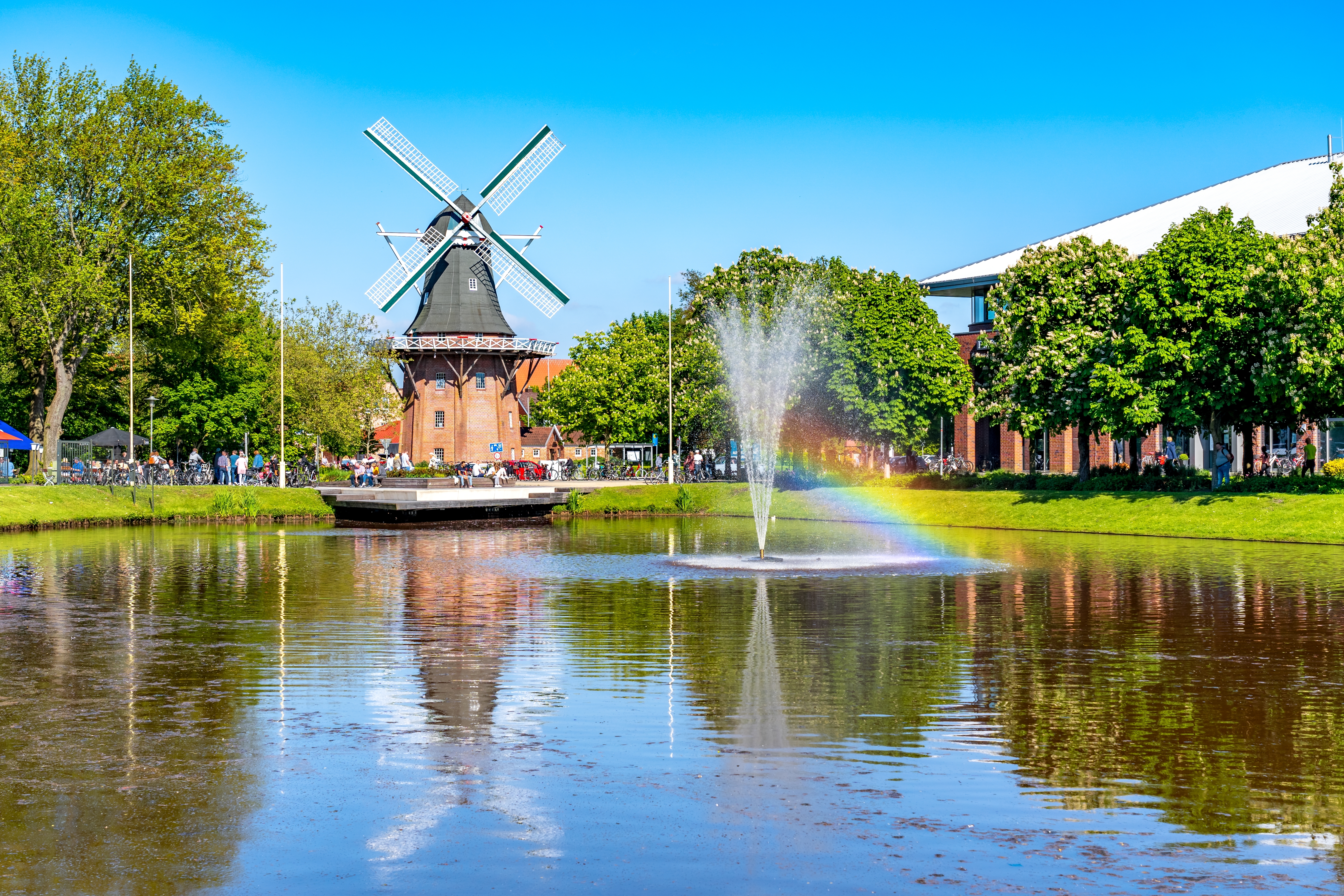 Traditionel vindmølle med springvand og regnbue reflekteret i kanal Tyskland