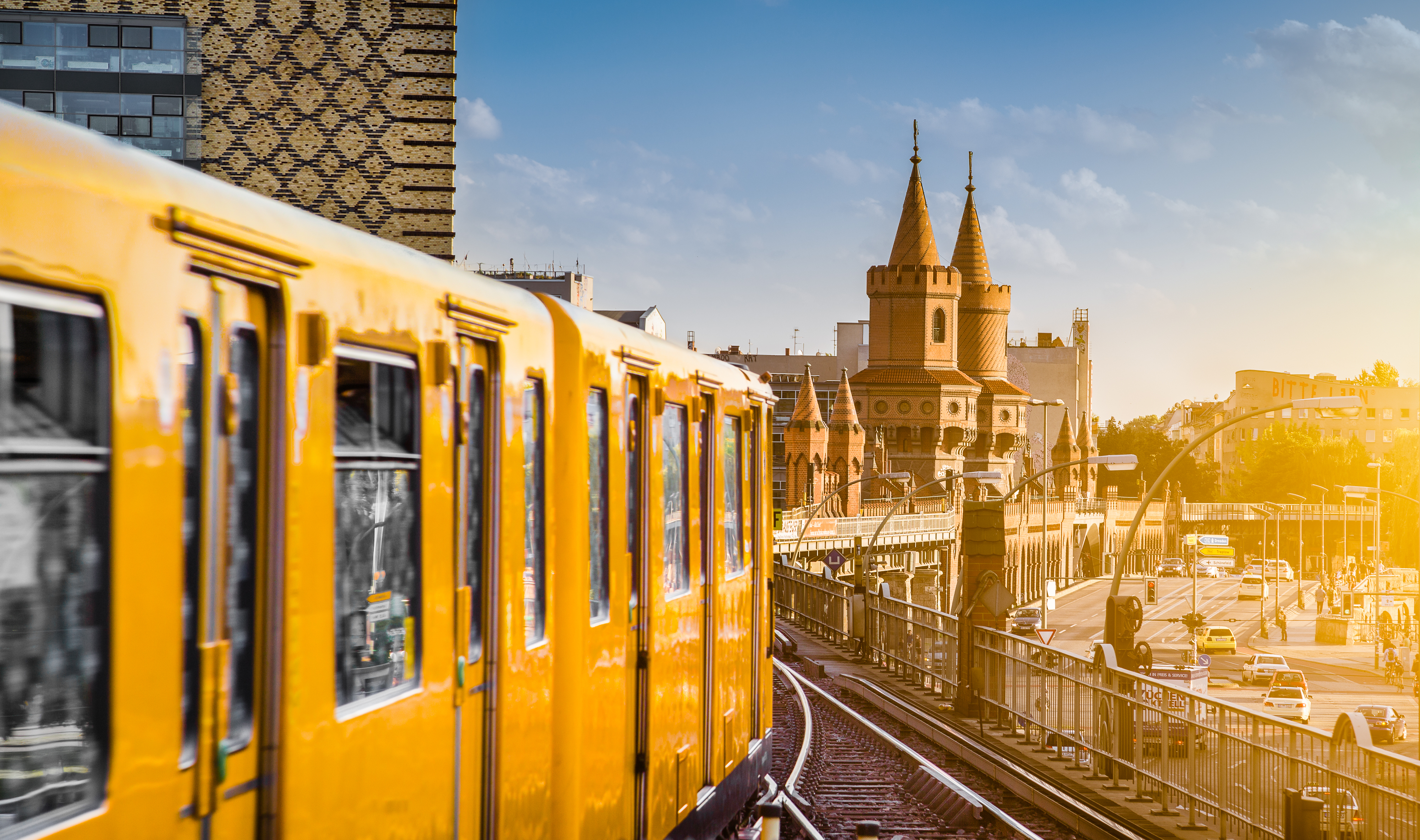 Gul Berlin metro på historisk bro med tårne ved solnedgang