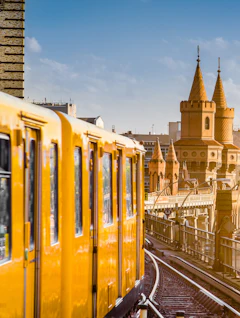 Gul Berlin metro på historisk bro med tårne ved solnedgang