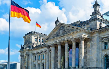 Den majestætiske Rigsdagsbygning i Berlin med glaskuppel og tysk flag, et populært rejsemål i Tyskland