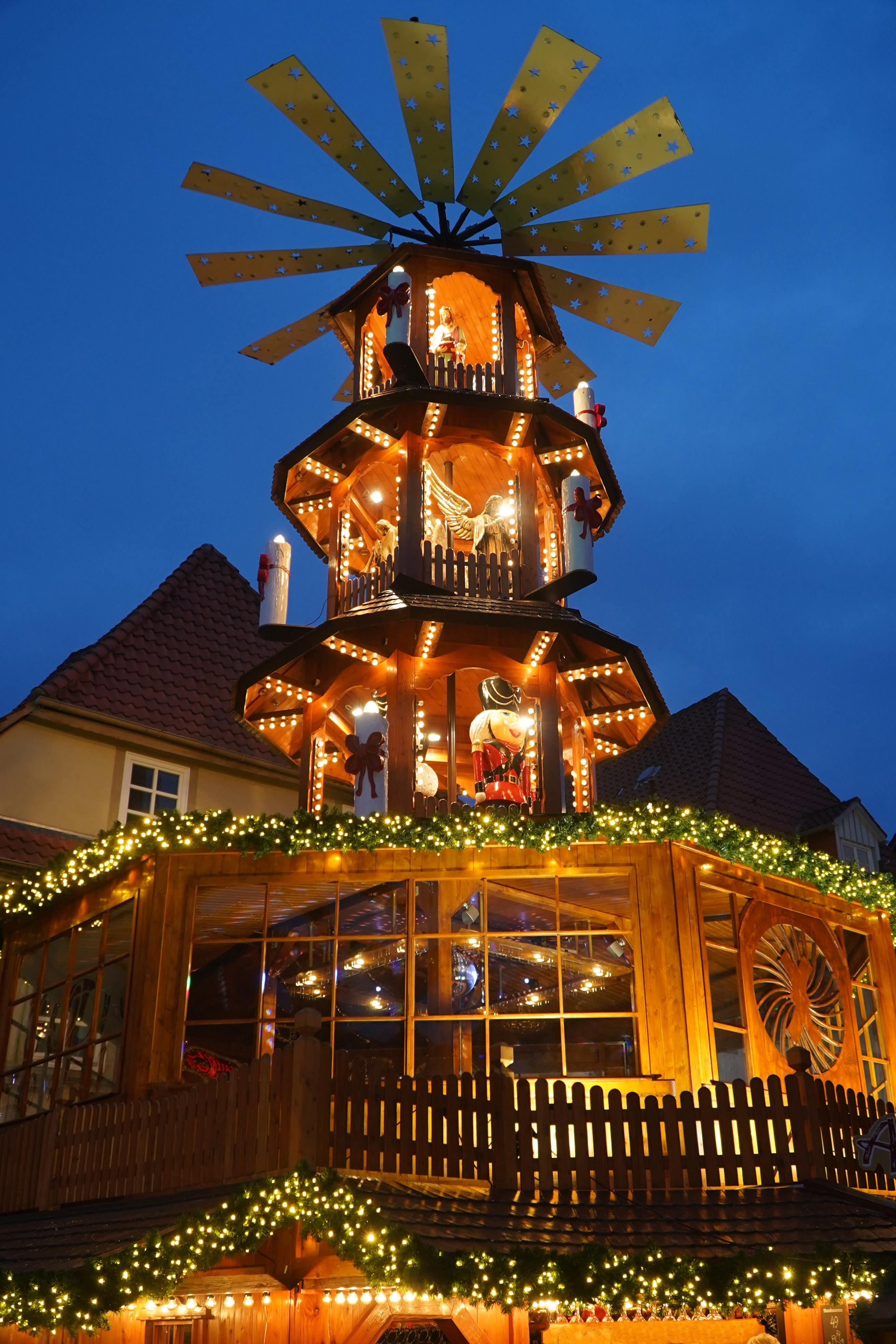 Eventyrlig julestemning ved den oplyste julepyramide på det historiske julemarked i Hameln, Niedersachsen, hvor træboder og gæster nydet den festlige atmosfære