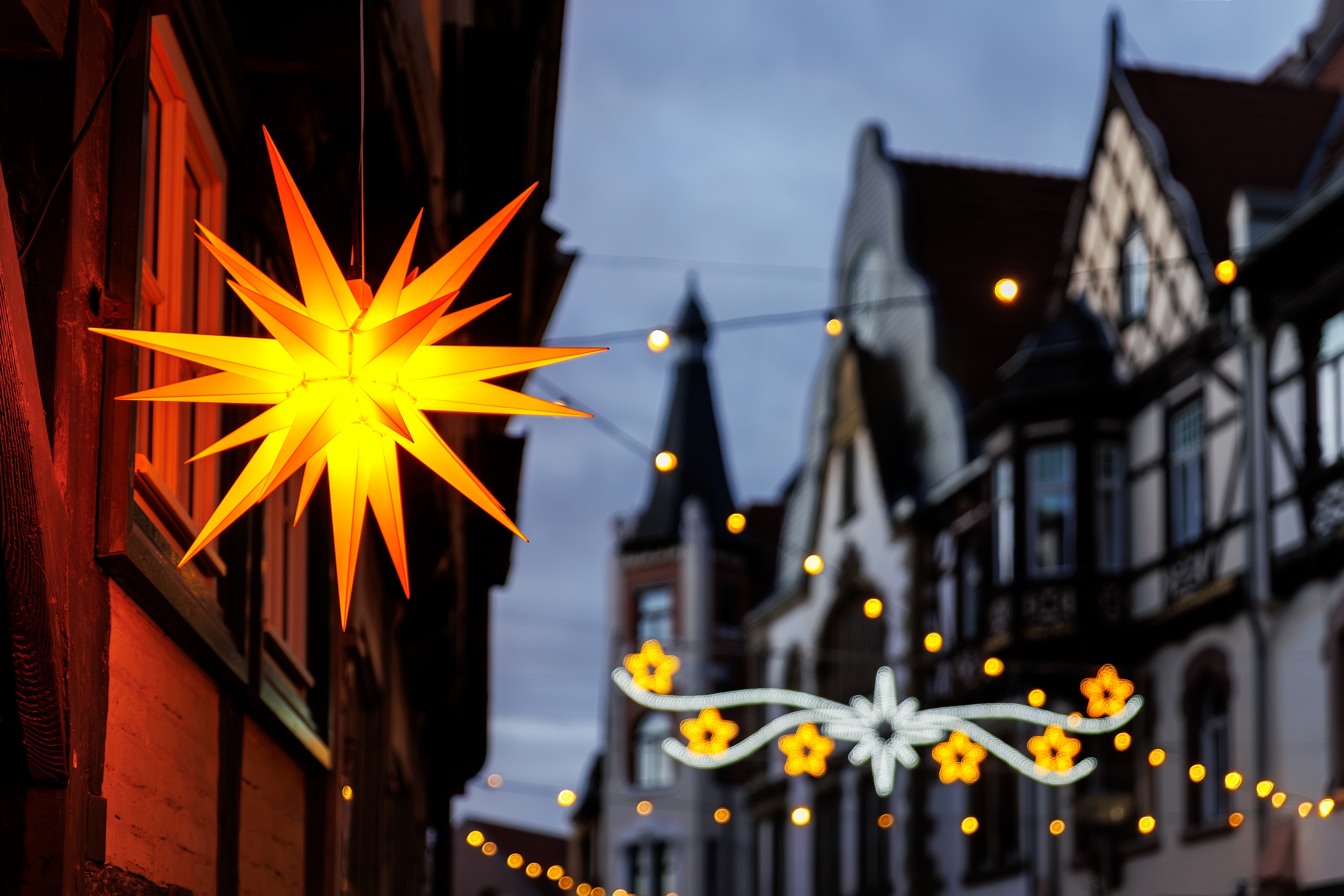 Julestemning i Wernigerode med lysende orangegul Herrnhut-stjerne og dekorative julelys langs historisk bindingsværksgade i Tyskland