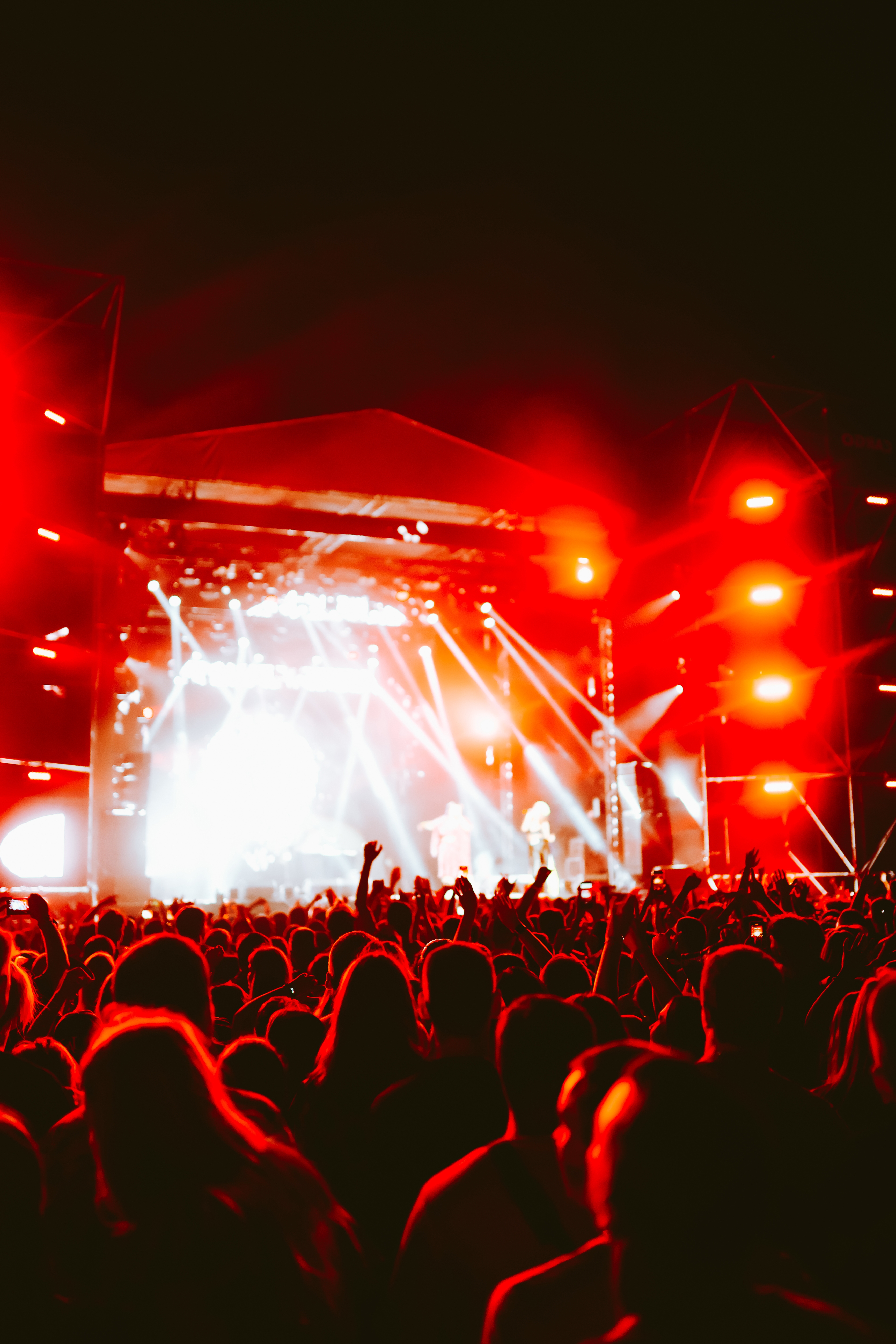 Energifyldt udendørs musikfestival om natten med jublende menneskemængde og farverige scenelys