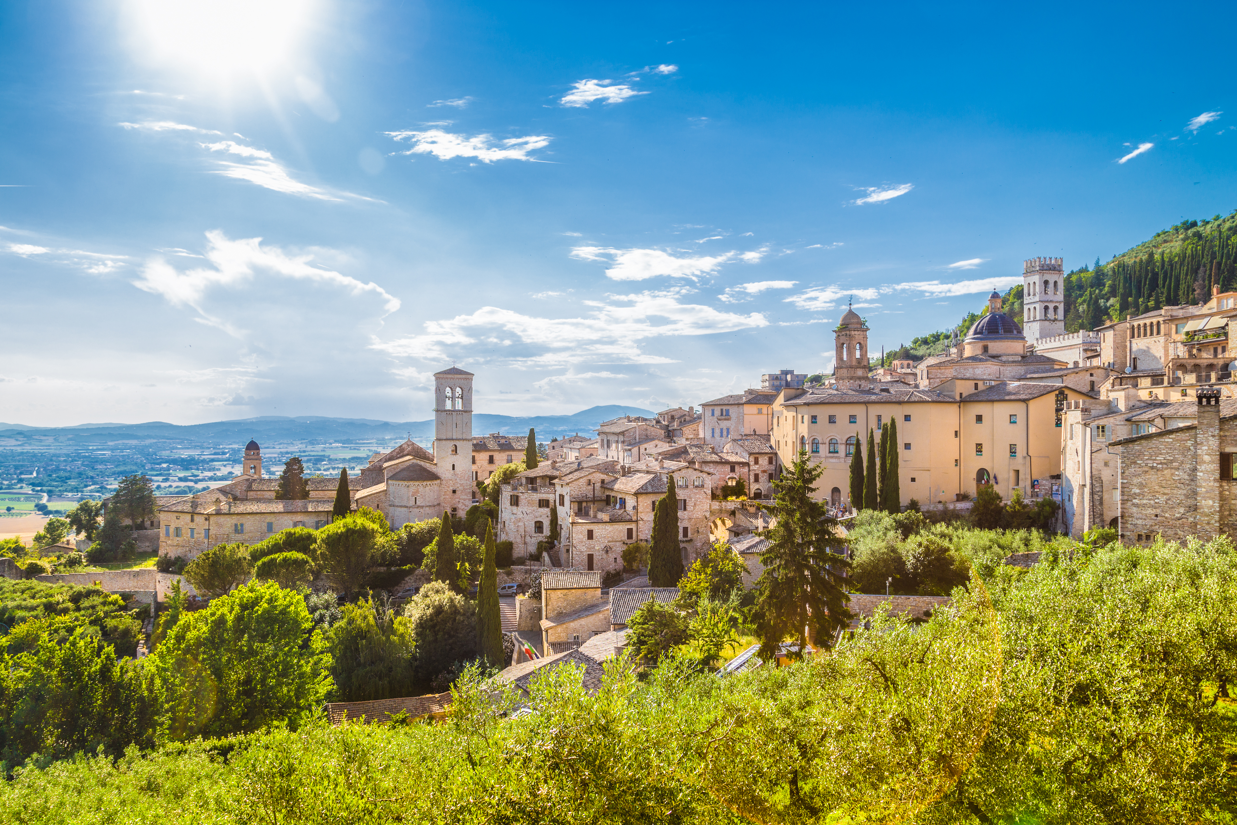 Den smukke klosterby Assisi i det grønne Umbrien landskab under solrig italiensk himmel