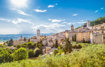 Den smukke klosterby Assisi i det grønne Umbrien landskab under solrig italiensk himmel