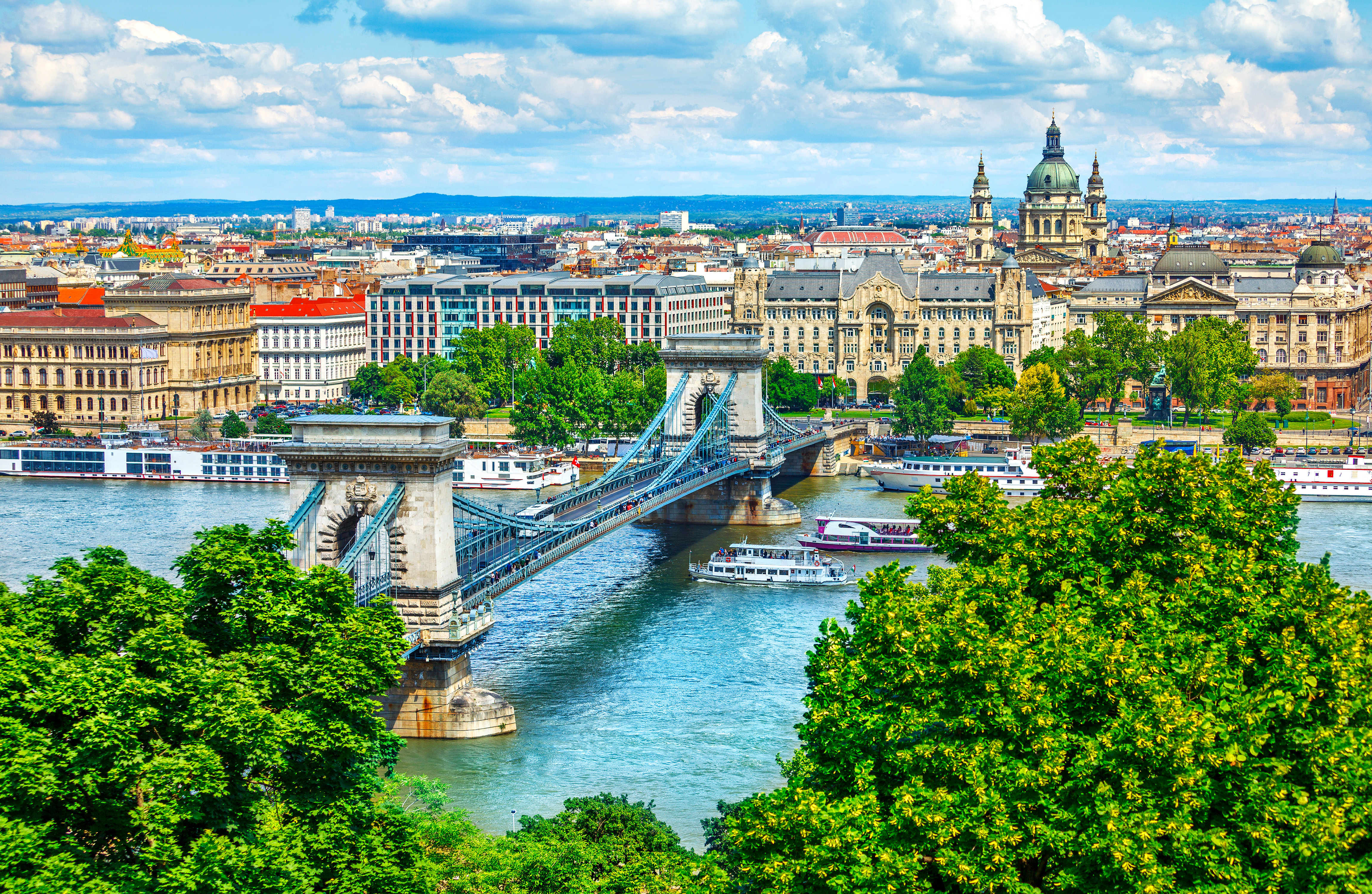 Luftudsigt over Budapest Kædebroen og Donau med grønne træer og blå himmel