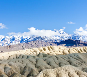 Vintersceneri fra Death Valley nationalpark med guldbrune klippeformationer og snedækkede bjergtinder