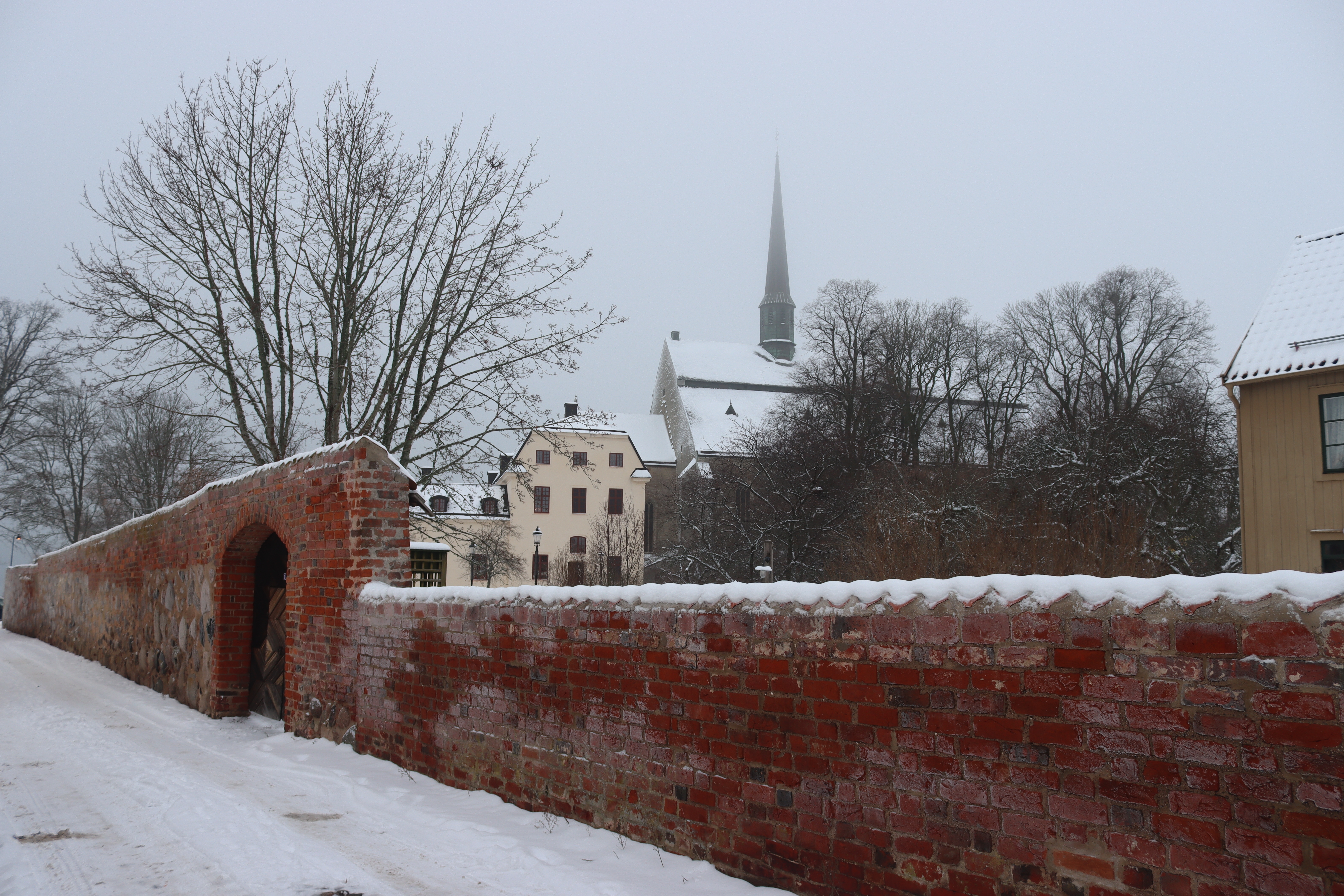 Vinterbillede af Vadstena i Østergötland med karakteristisk rød murstensmur og snedækkede tage ved den historiske kirke