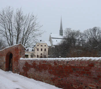Vinterbillede af Vadstena i Østergötland med karakteristisk rød murstensmur og snedækkede tage ved den historiske kirke
