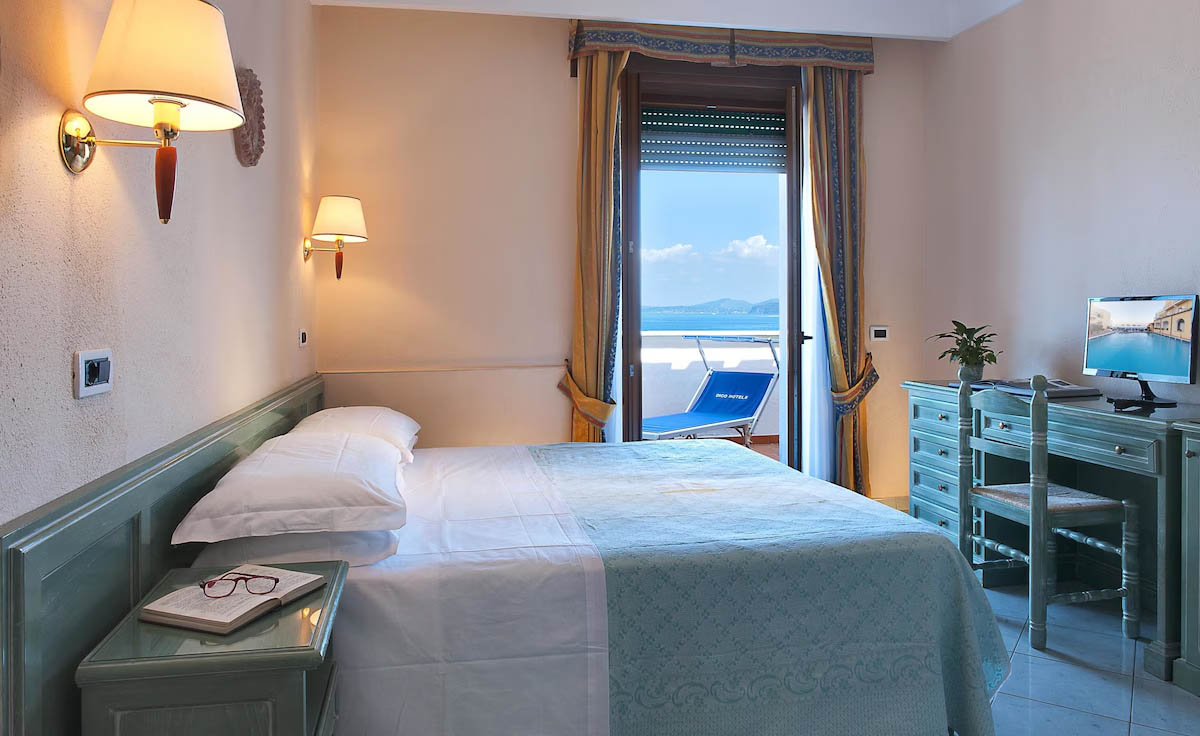 Komfortabelt hotelværelse på Ischia med dobbeltseng og balkon med udsigt til havet