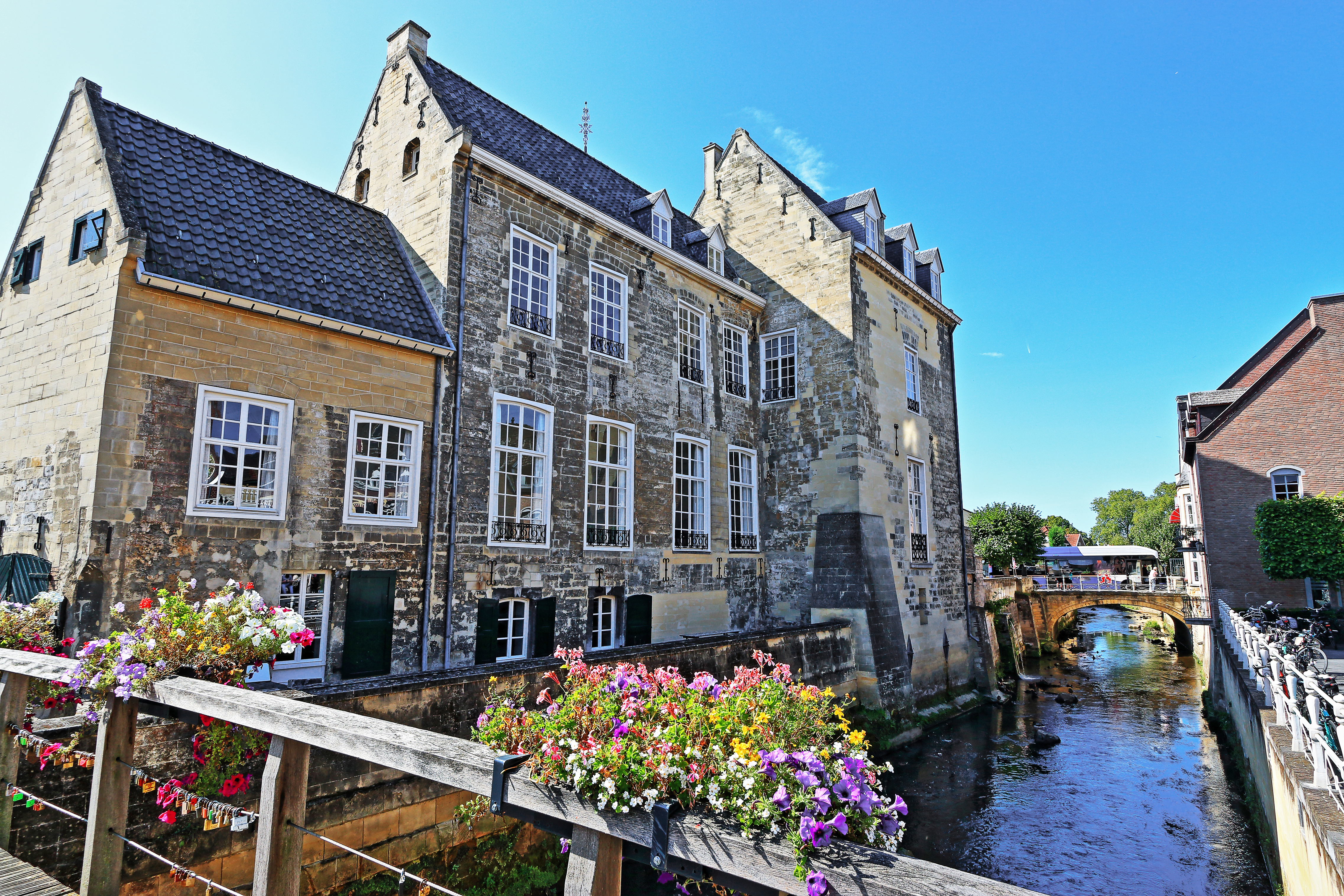 Den charmerende middelalderborg Burg den Halder ved floden Geul i Valkenburg, Limburg, Holland, med farverige blomster på broen