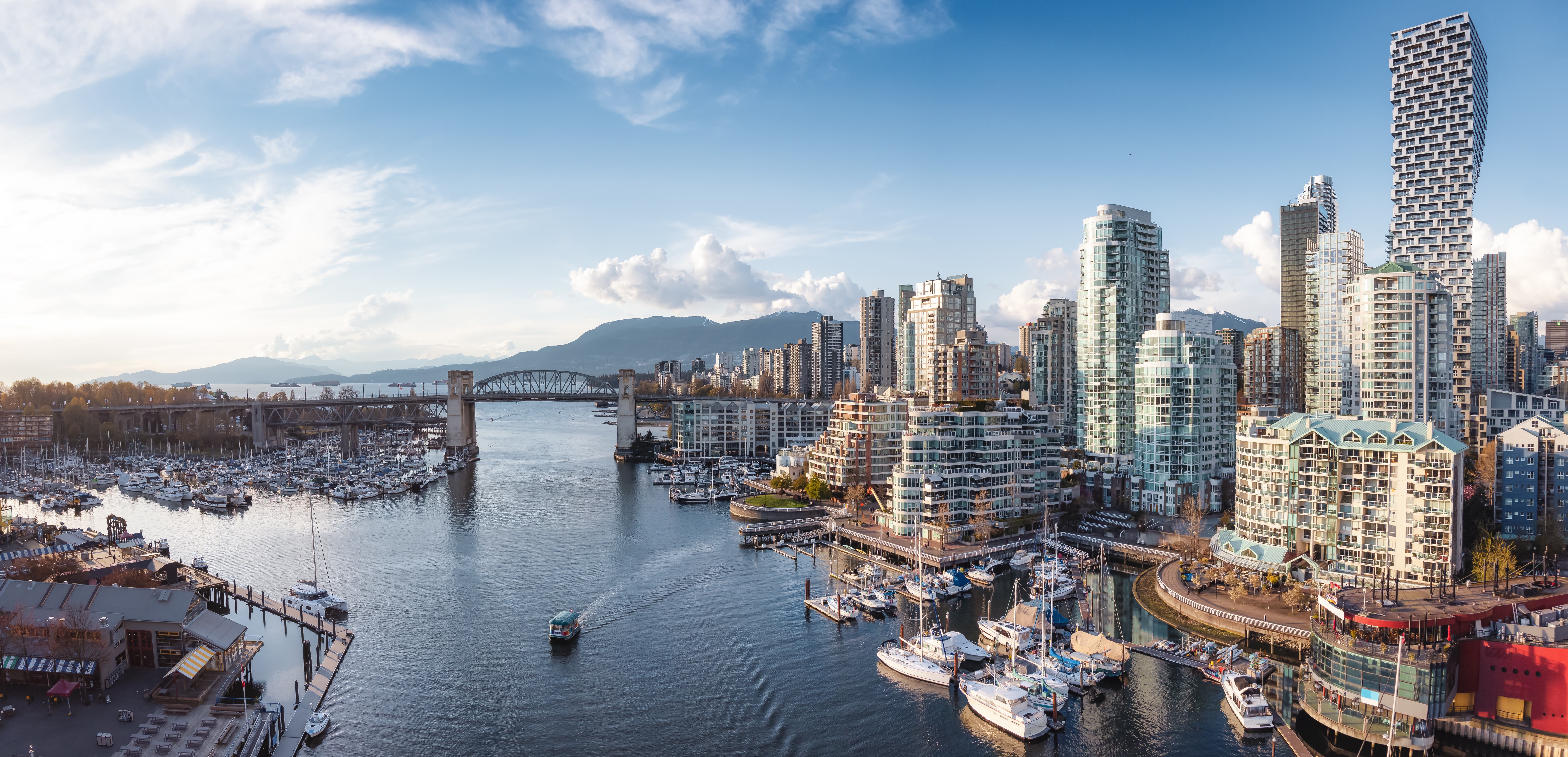 Storslået panorama af Vancouver bymidte med False Creek marina, højhuse og bjerglandskab i baggrunden