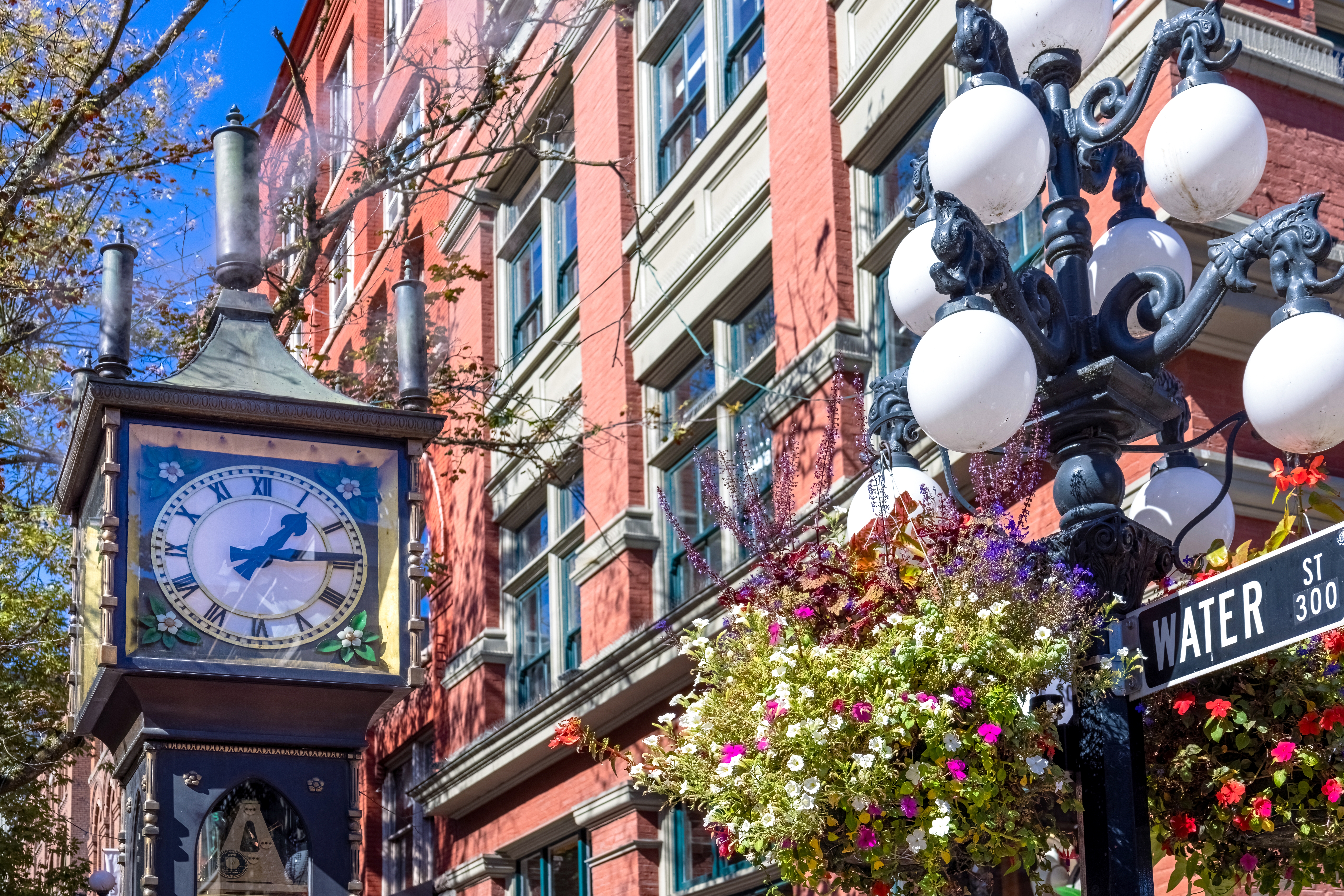 Seværdighed i Vancouver – den kendte dampuhr på Water Street i Gastown omgivet af farverige blomster og historisk arkitektur i British Columbia, Canada