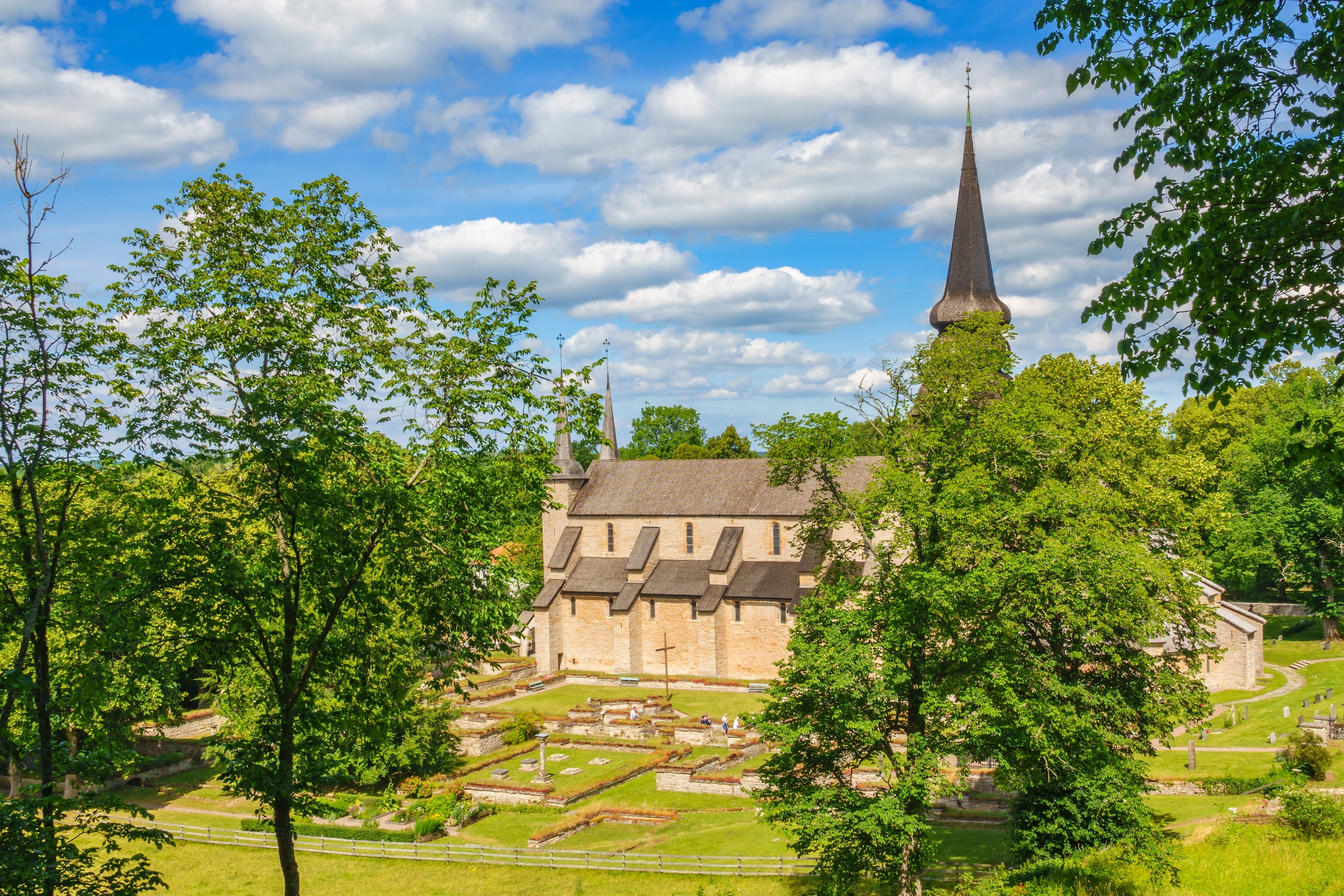 Varnhem Cistercienserkloster i Sverige set fra afstand med grøn natur og blå sommerhimmel