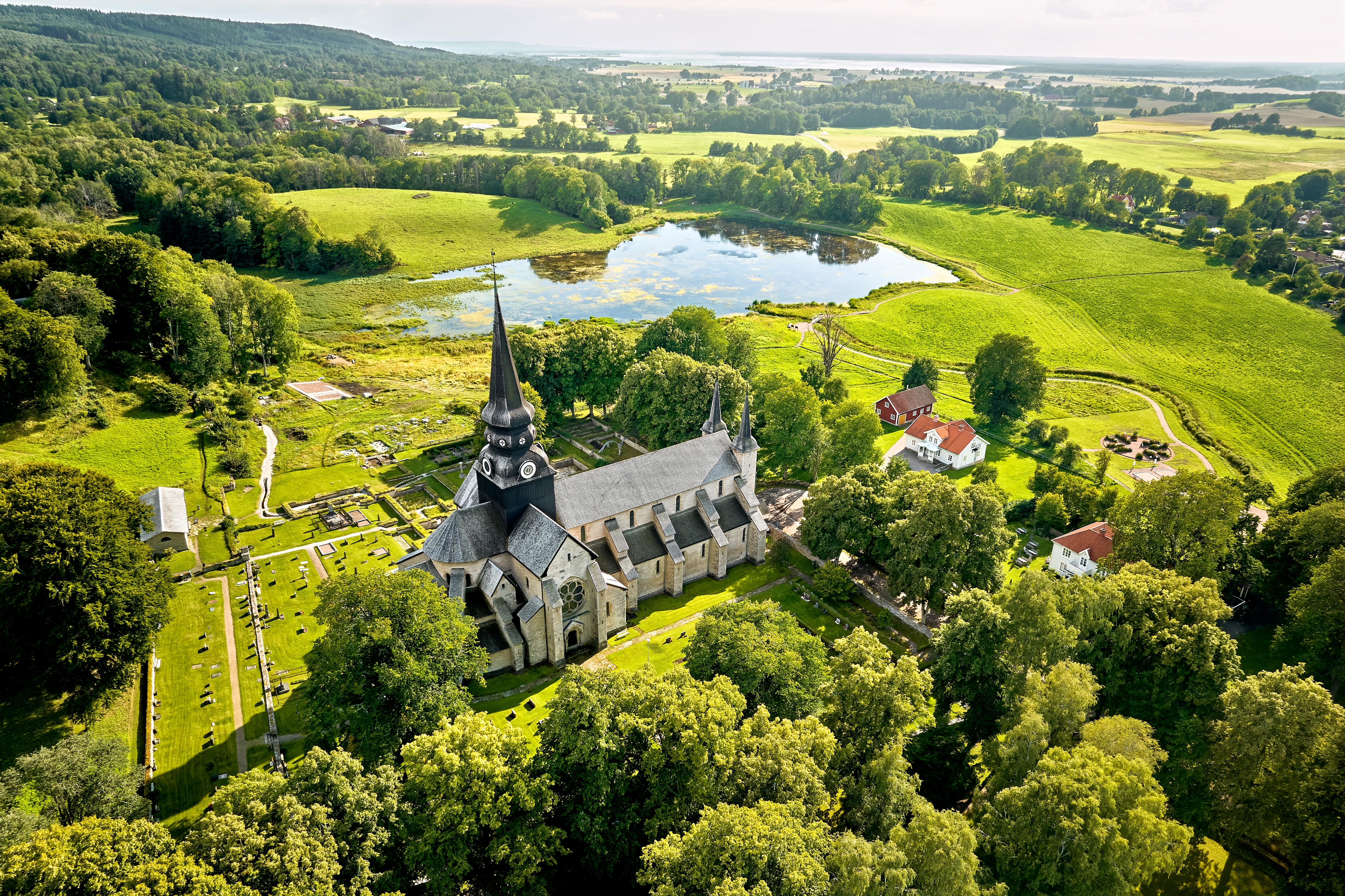 Smukt luftfoto af Varnhem Kloster i Vestergötland, Sverige, med Klostersjön og de grønne sommerlandskaber omkring det historiske kloster