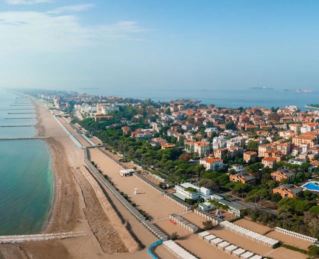 Smukt luftfoto af Lido di Venezia med lang sandstrand, grønne træer og udsigt over Venedigs lagune, Italien