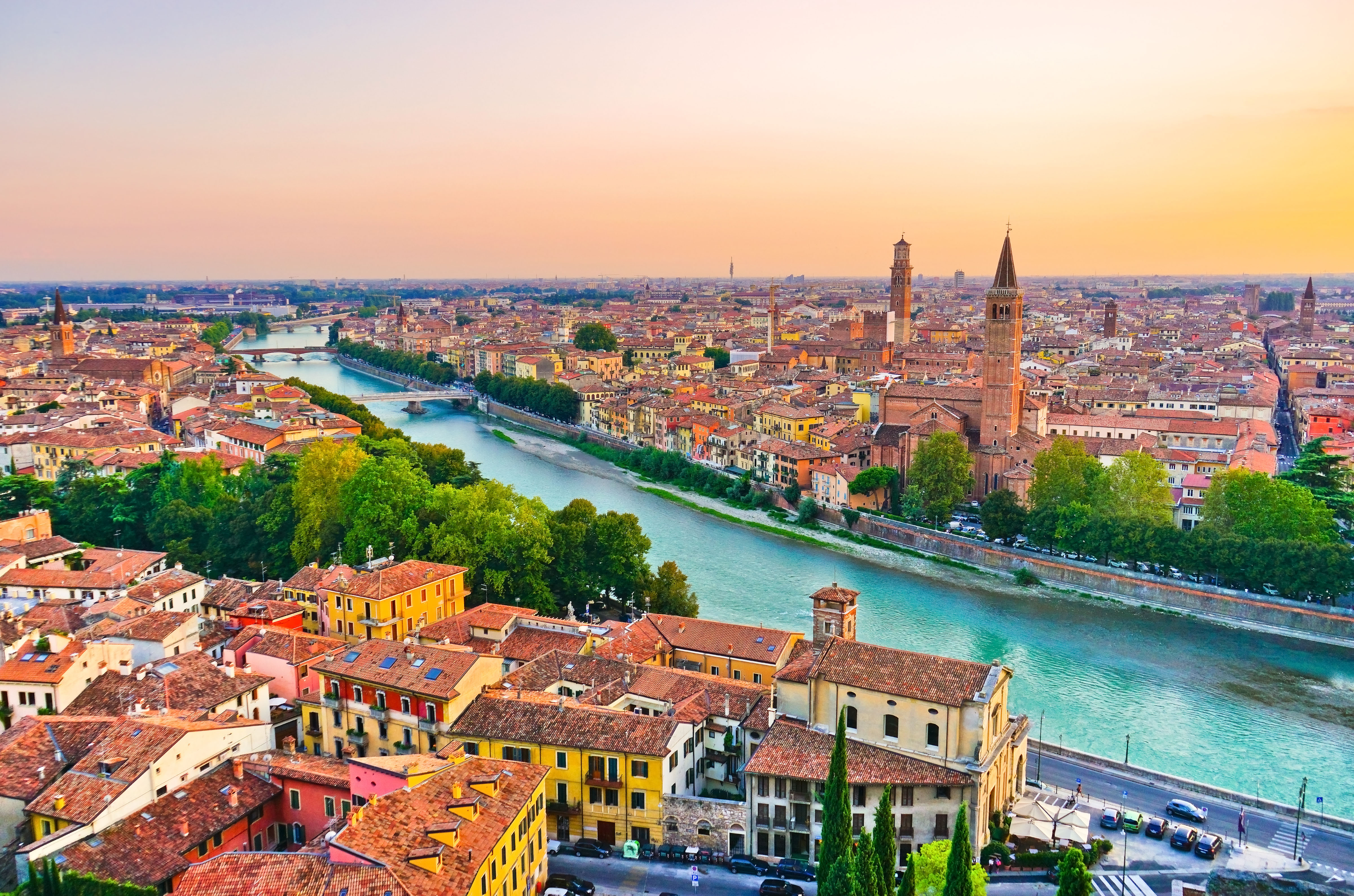 Idyllisk solnedgangsudsigt over Verona med den snoede Adige-flod, historiske bygninger og middelalderlige tårne i det nordlige Italien
