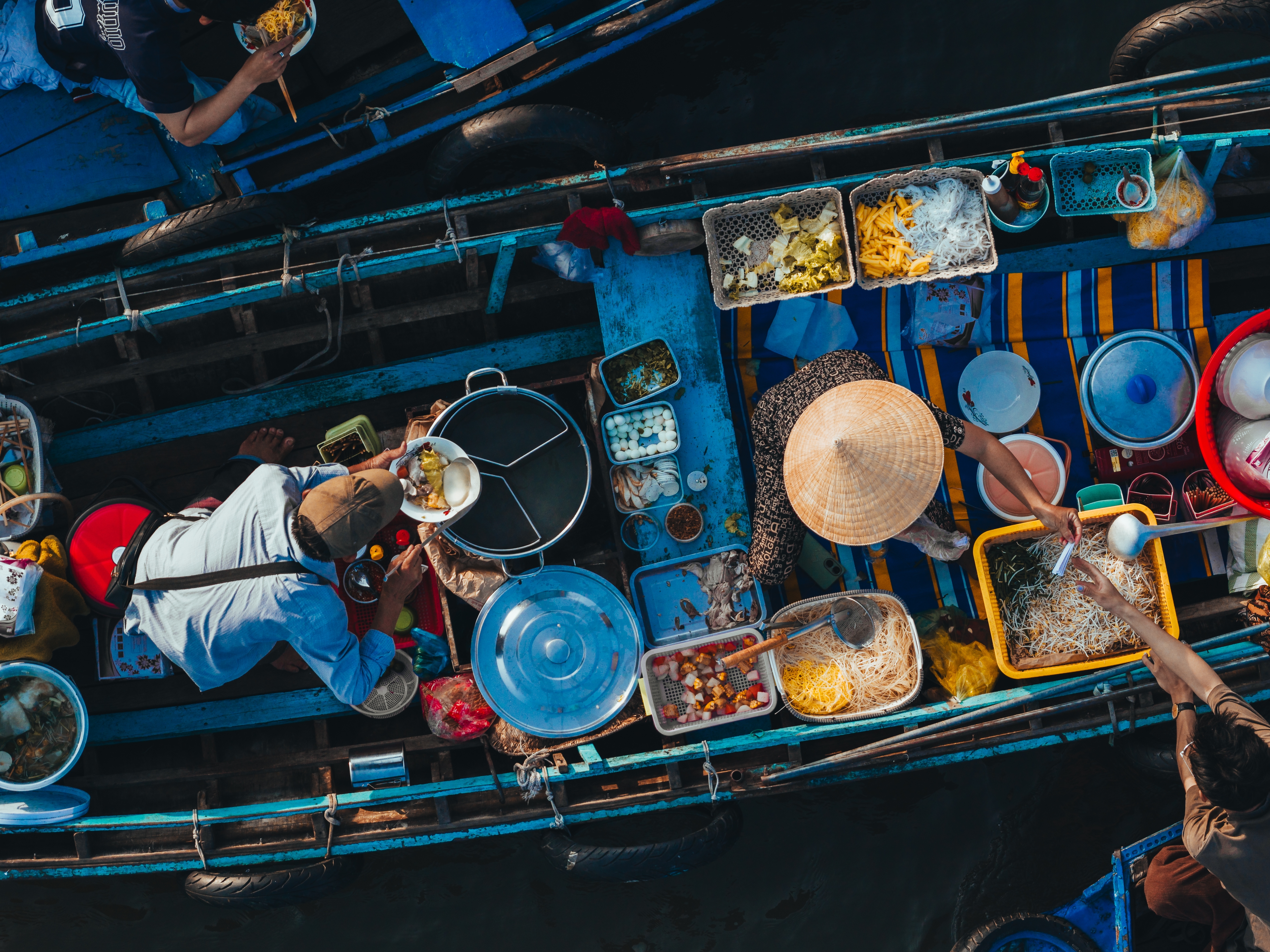 Luftfoto af det farverige flydende marked Cai Rang i Can Tho på Mekong Delta i Vietnam, hvor lokale sælger frisk mad fra traditionelle træbåde