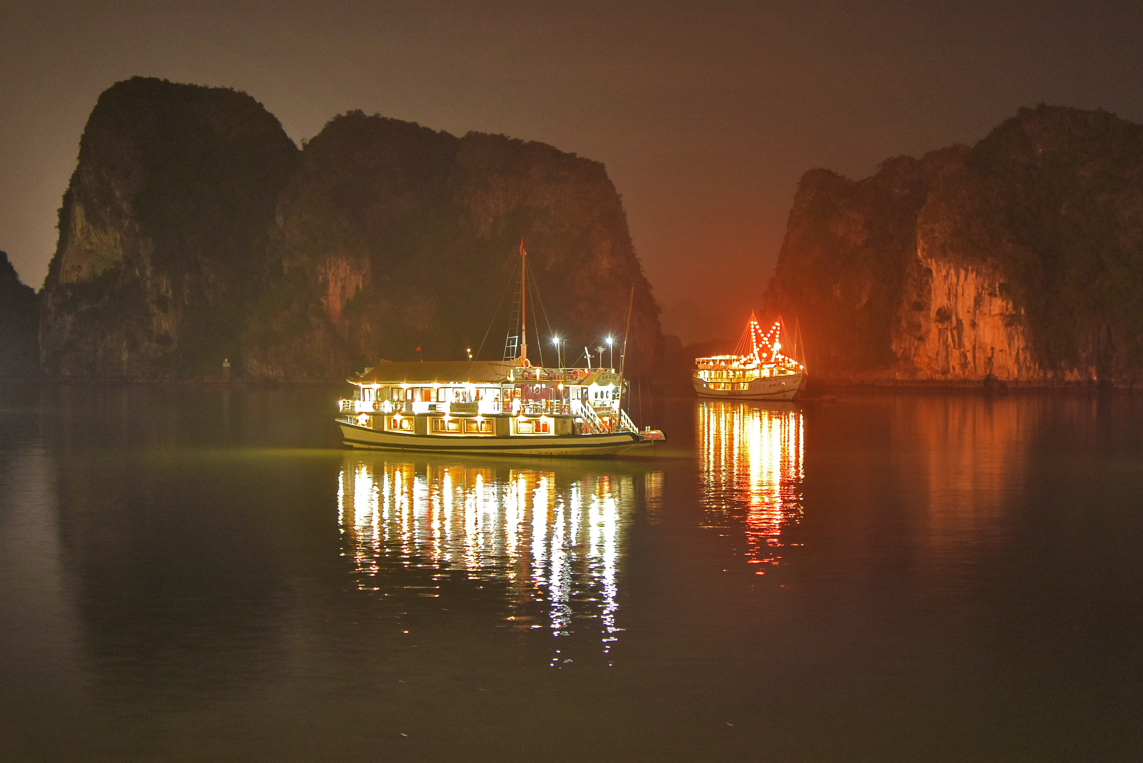 Romantisk aftenstemning i Ha Long Bay Vietnam med cruise både og refleksioner i det stille vand