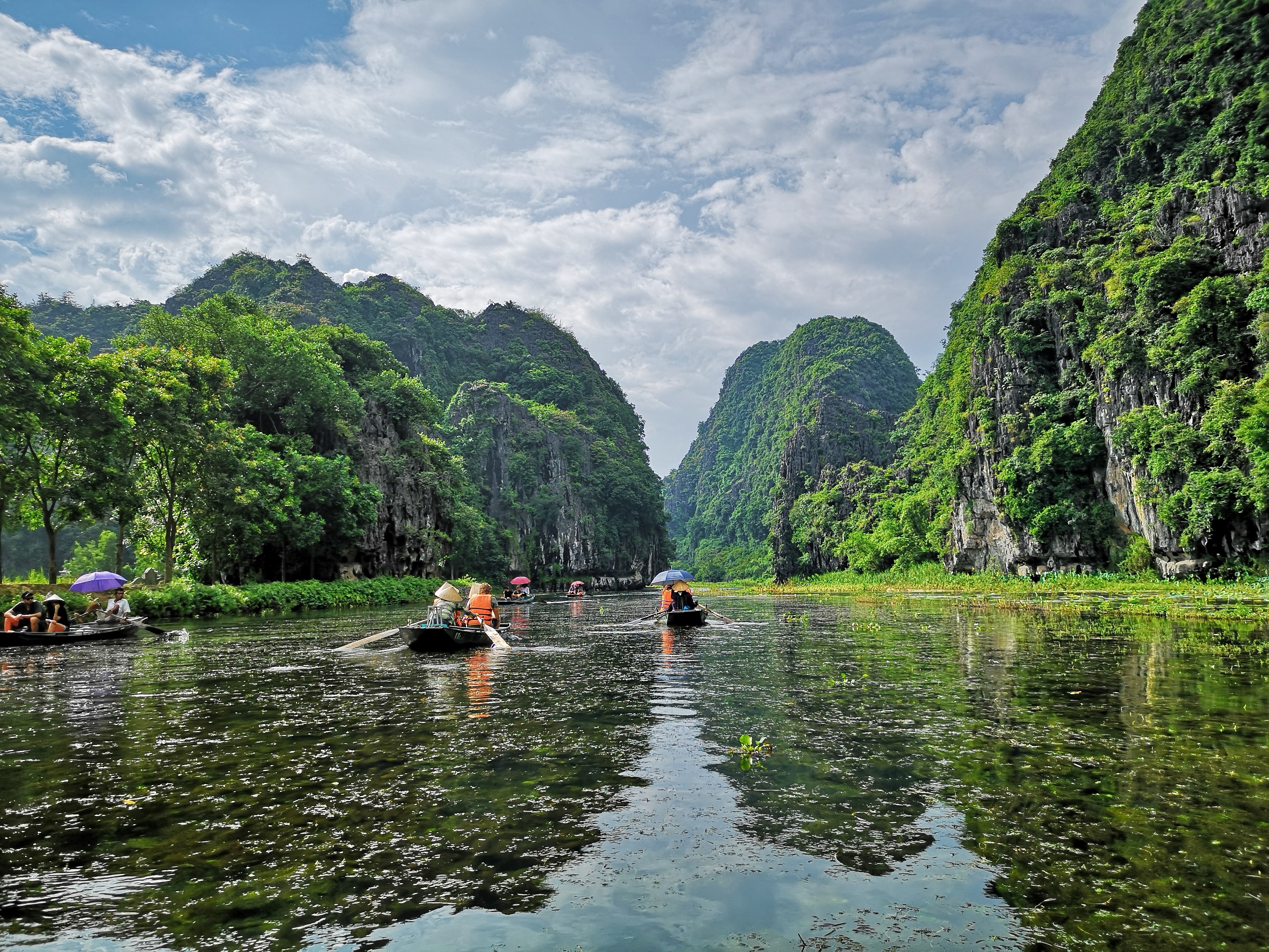 Rolig bådfart gennem smukke kalkstenslandskaber og grønne bjerge i Ninh Binh Vietnam