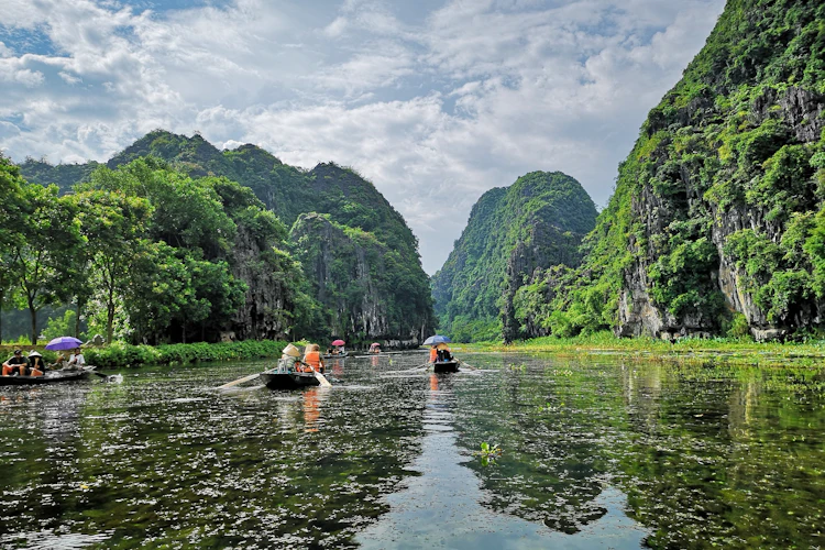 Rolig bådfart gennem smukke kalkstenslandskaber og grønne bjerge i Ninh Binh Vietnam