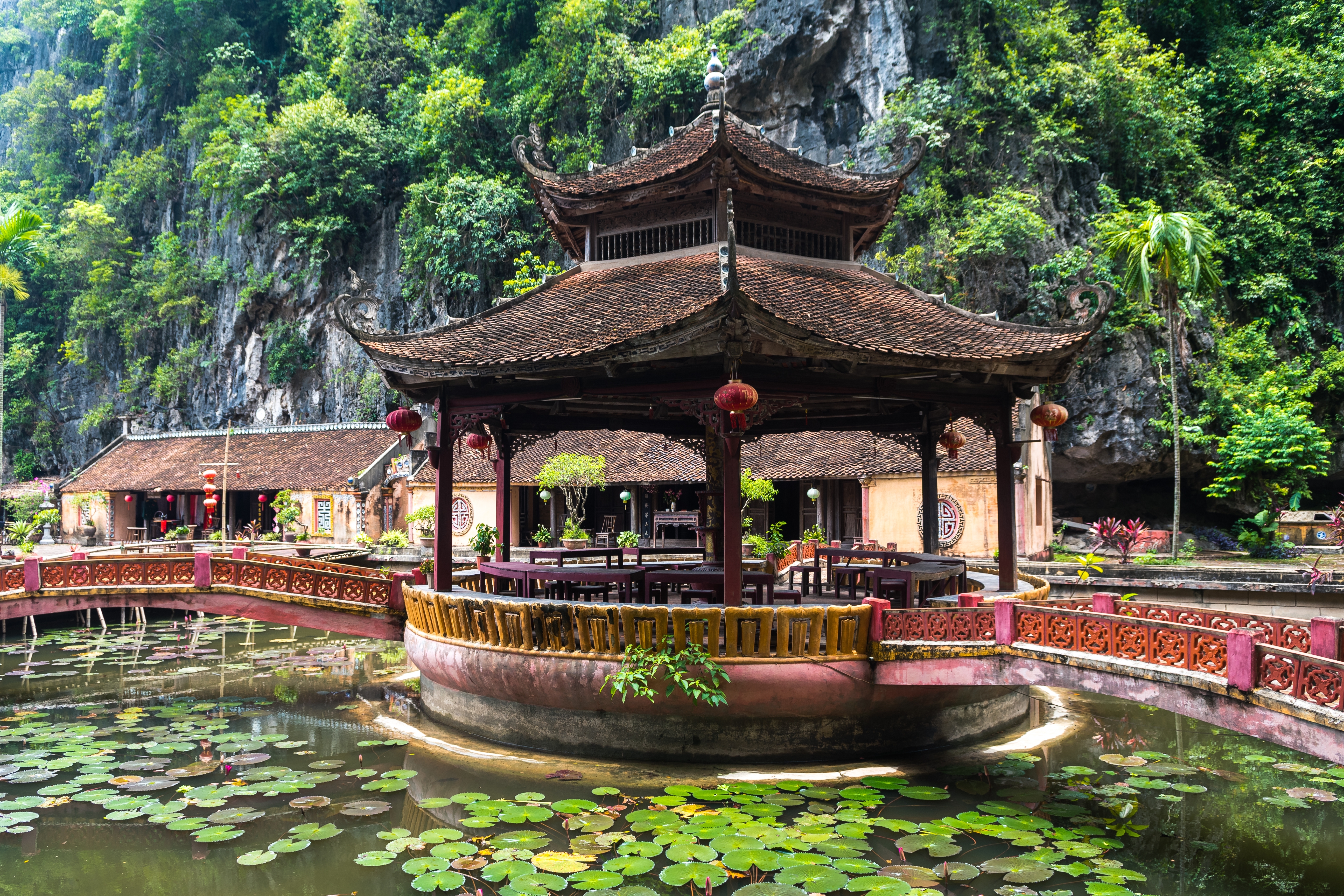 Traditionel pagode ved Hoa Lu omgivet af en frodig lotusdam med dramatiske kalkstensklipper i baggrunden, Ninh Binh Vietnam