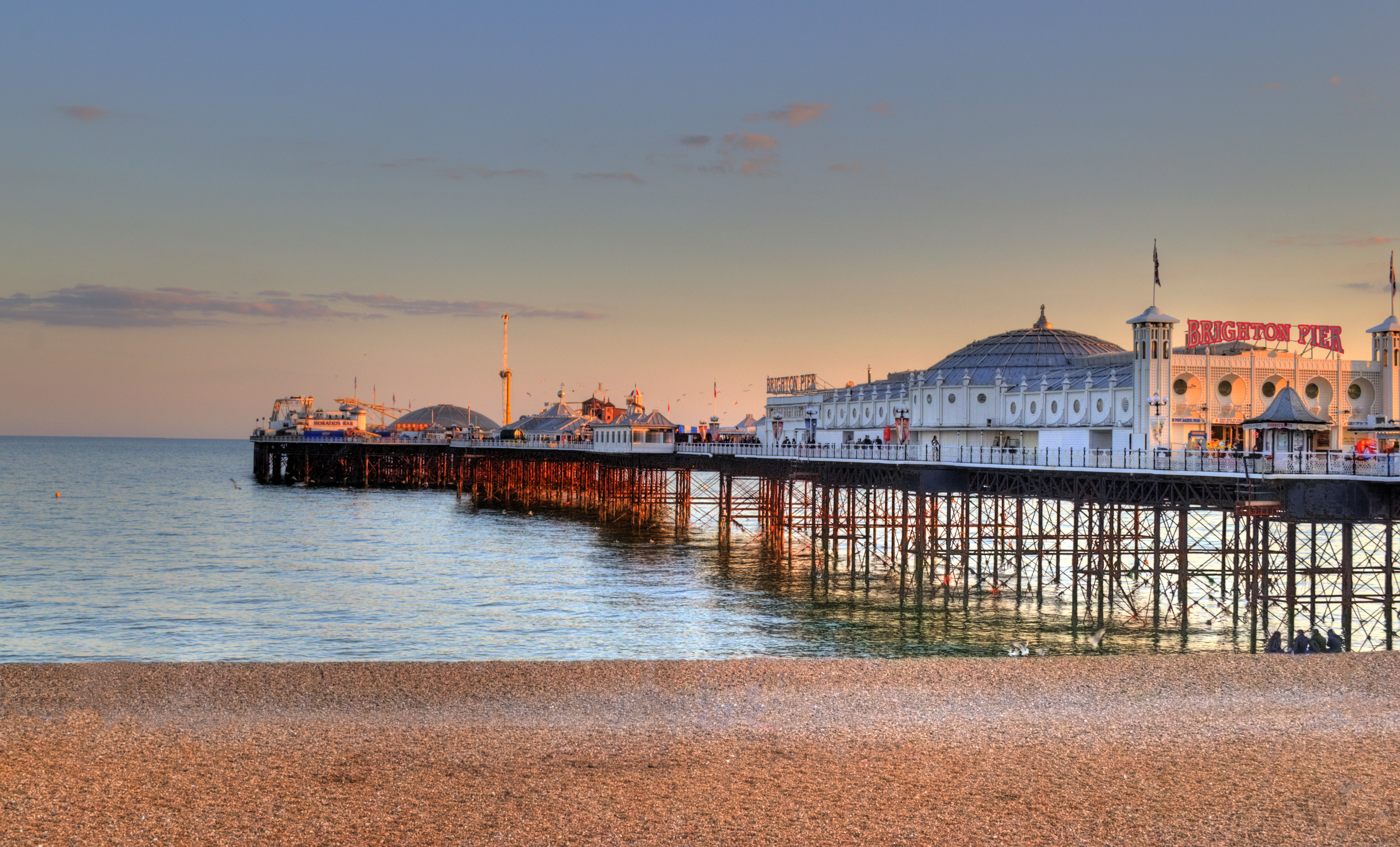 Victoriansk Brighton Pier med kuppelarkitektur og stenstrand i aftensol