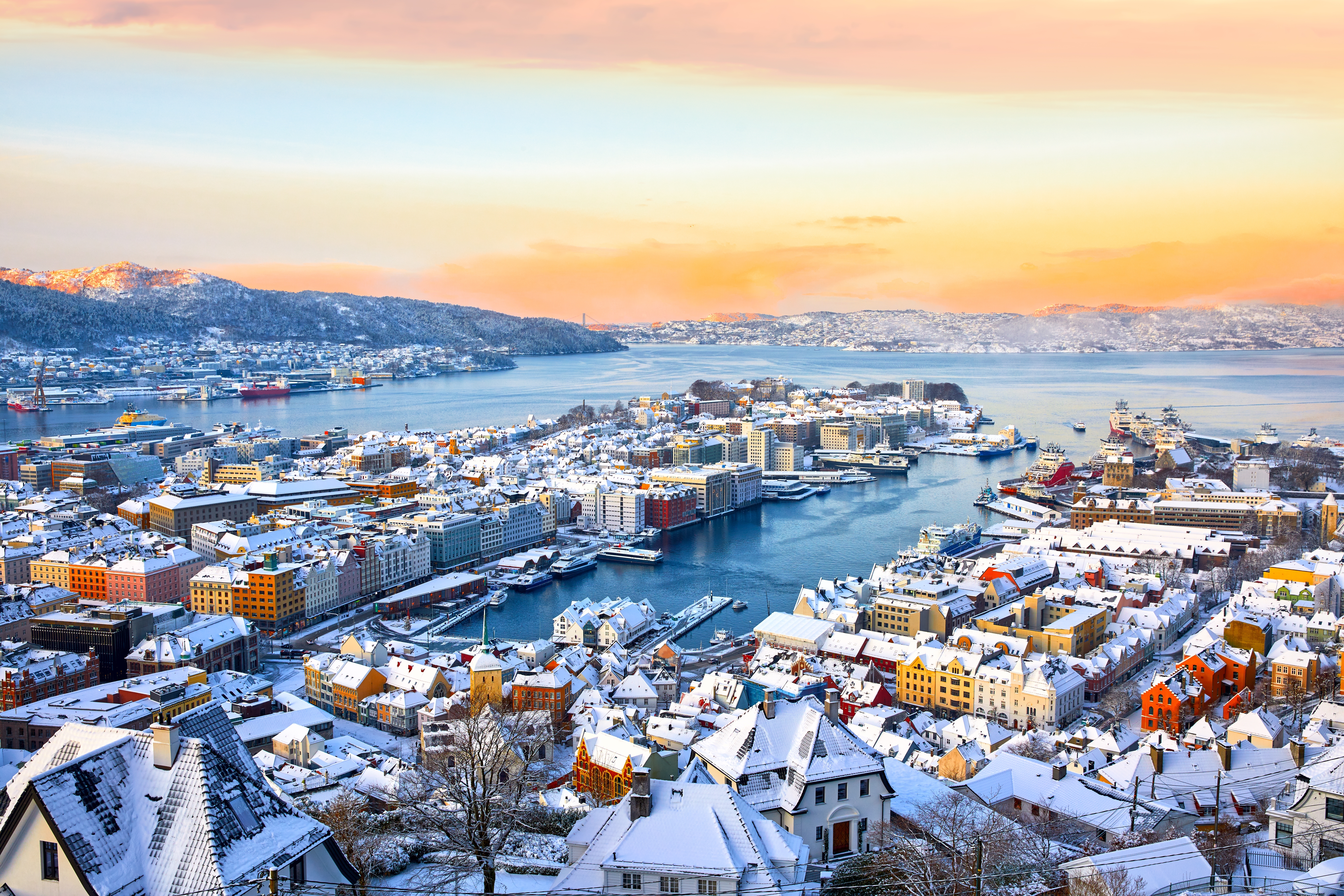 Spektakulær vinterlandskab over Bergen med snedækkede bygninger og havneområde