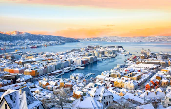 Spektakulær vinterlandskab over Bergen med snedækkede bygninger og havneområde