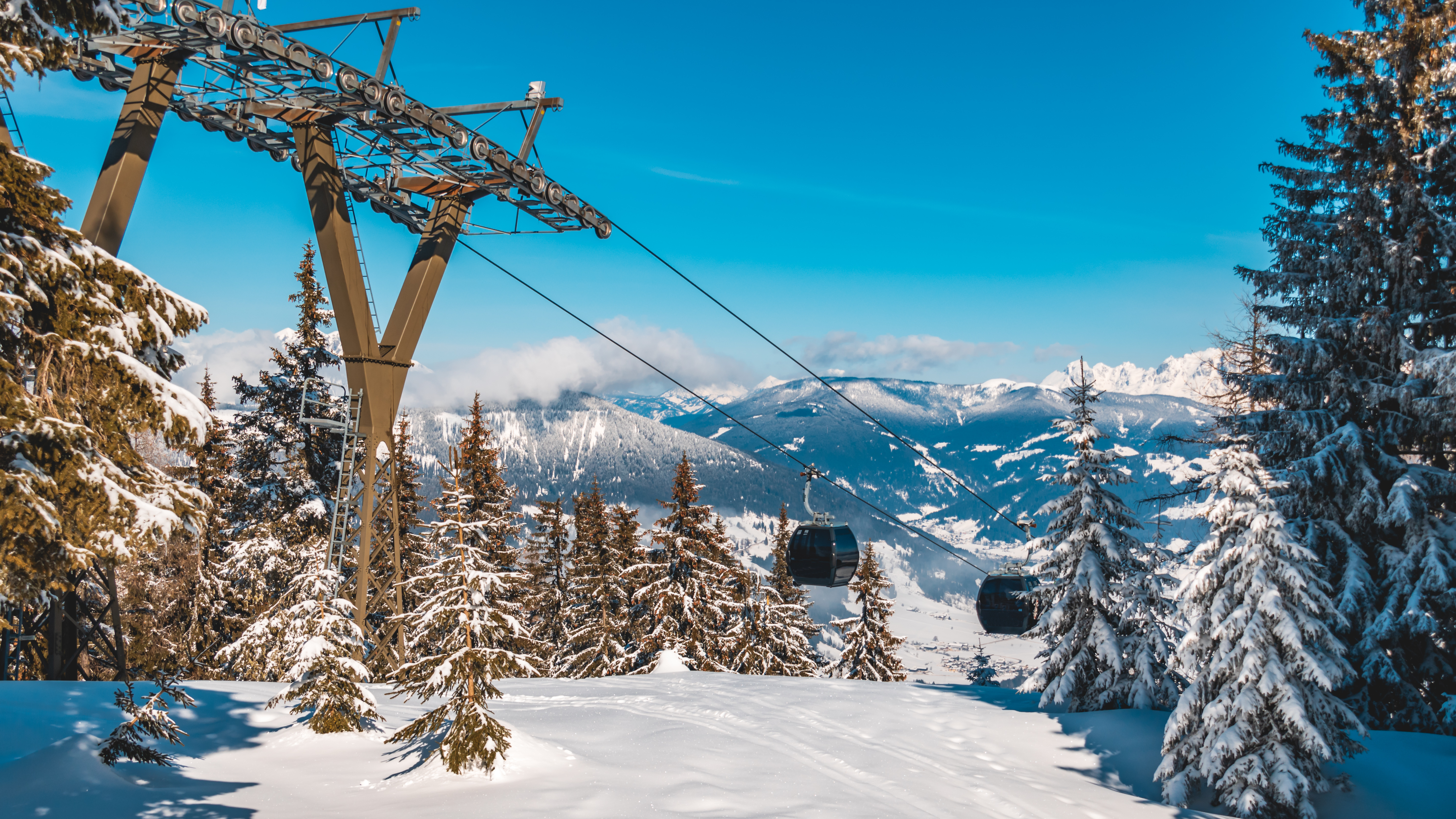 Gondollift i Flachau, Salzburg, Østrig omgivet af snedækkede grantræer og storslåede alpelandskaber på en solrig vinterdag