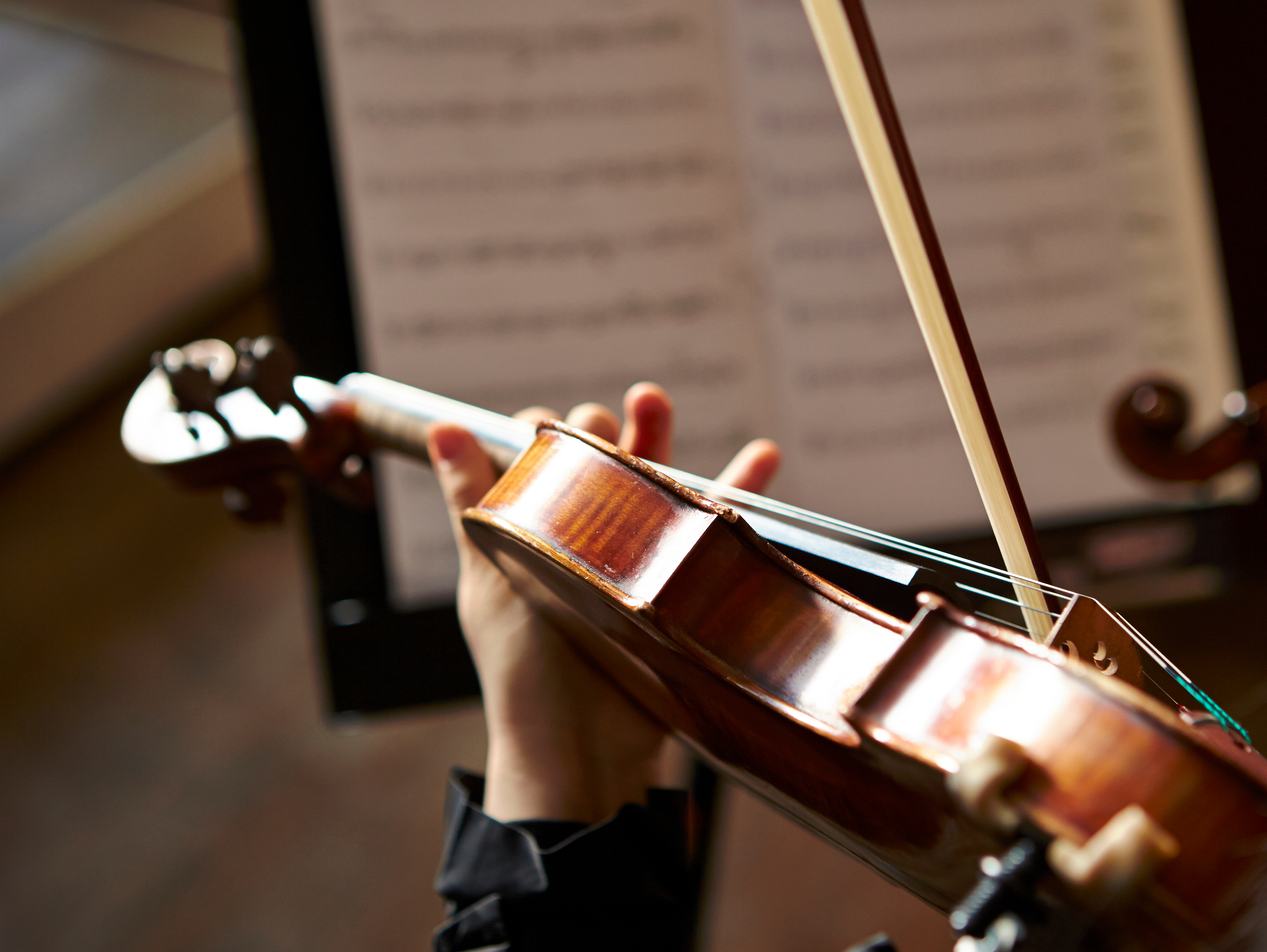 Professionel violinist spiller klassisk musik med noder opstillet foran sig ved orkesterkoncert