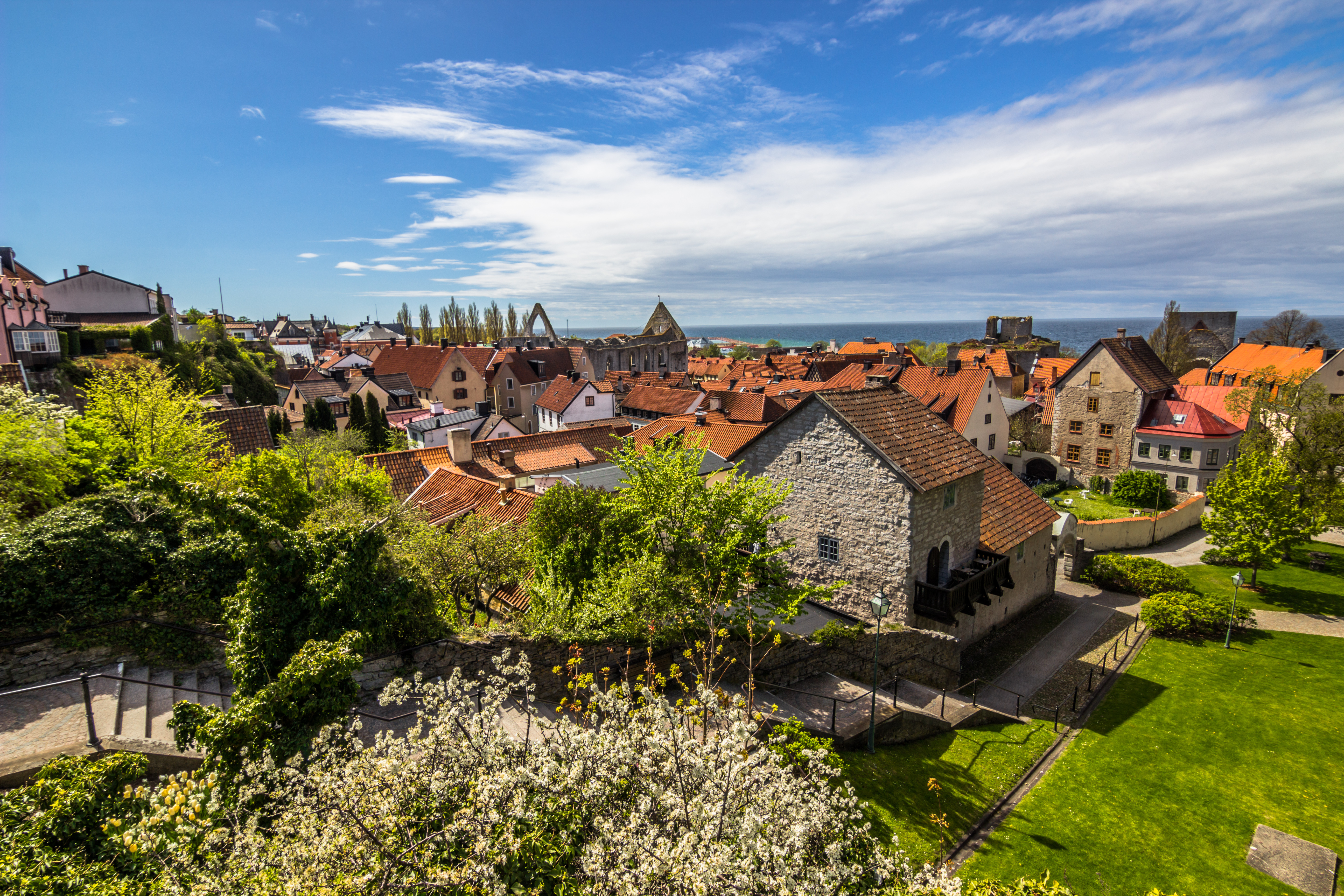 Fascinerende panorama af middelalderbyen Visby på Gotland, Sverige, med dens ikoniske bymur, historiske bygninger og kirketårne, der rejser sig over de røde tage omgivet af grønne træer