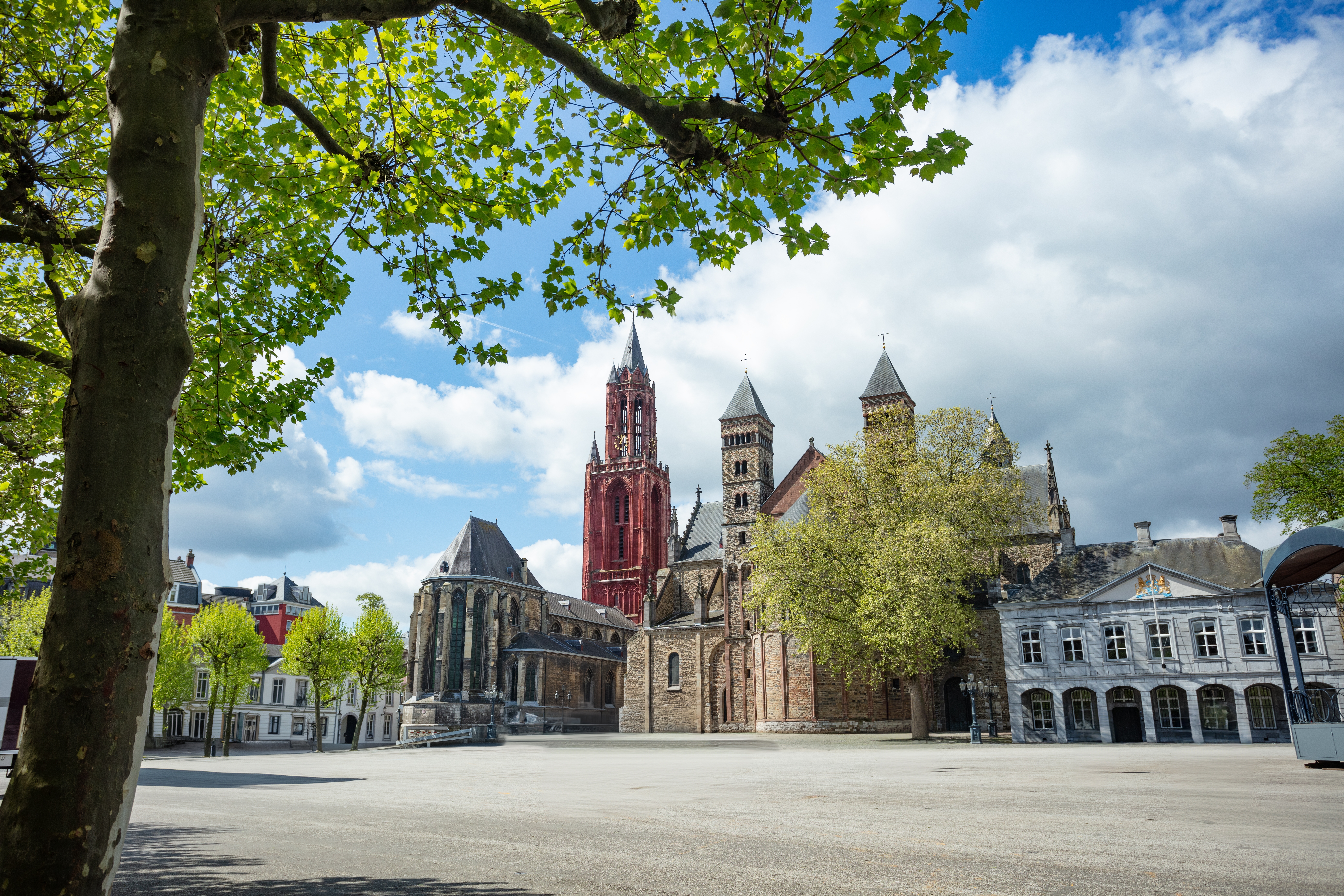 Den brede Vrijthof-plads i Maastricht med det karakteristiske røde kirketårn og historiske bygninger i foråret