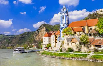 Wachau-dal ved Donau med klosterkirke og middelalderlige huse langs floden med passagerbåd