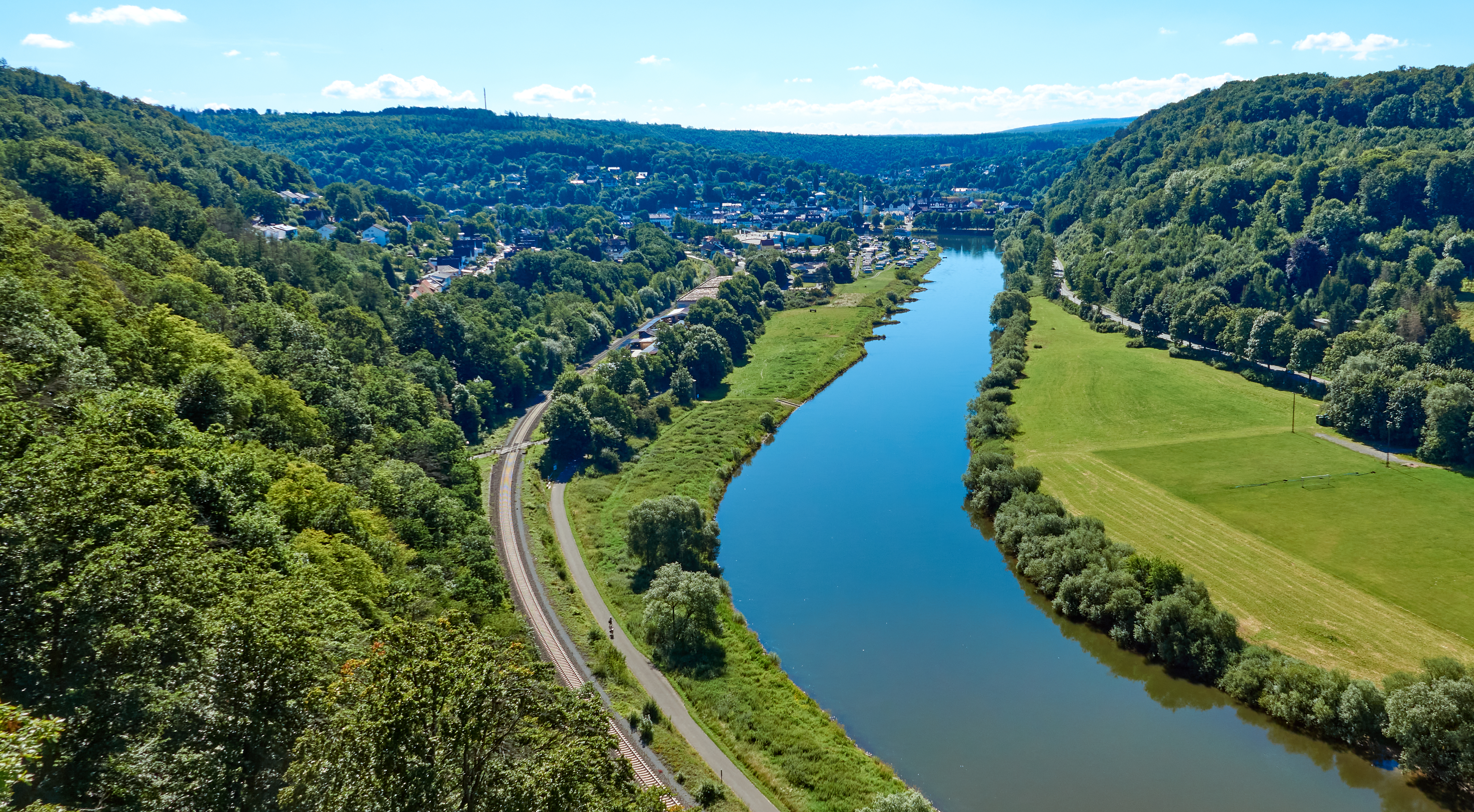 Luftfoto af den smukke Weser-flod nær Beverungen omgivet af grønne skove og marker i Tyskland