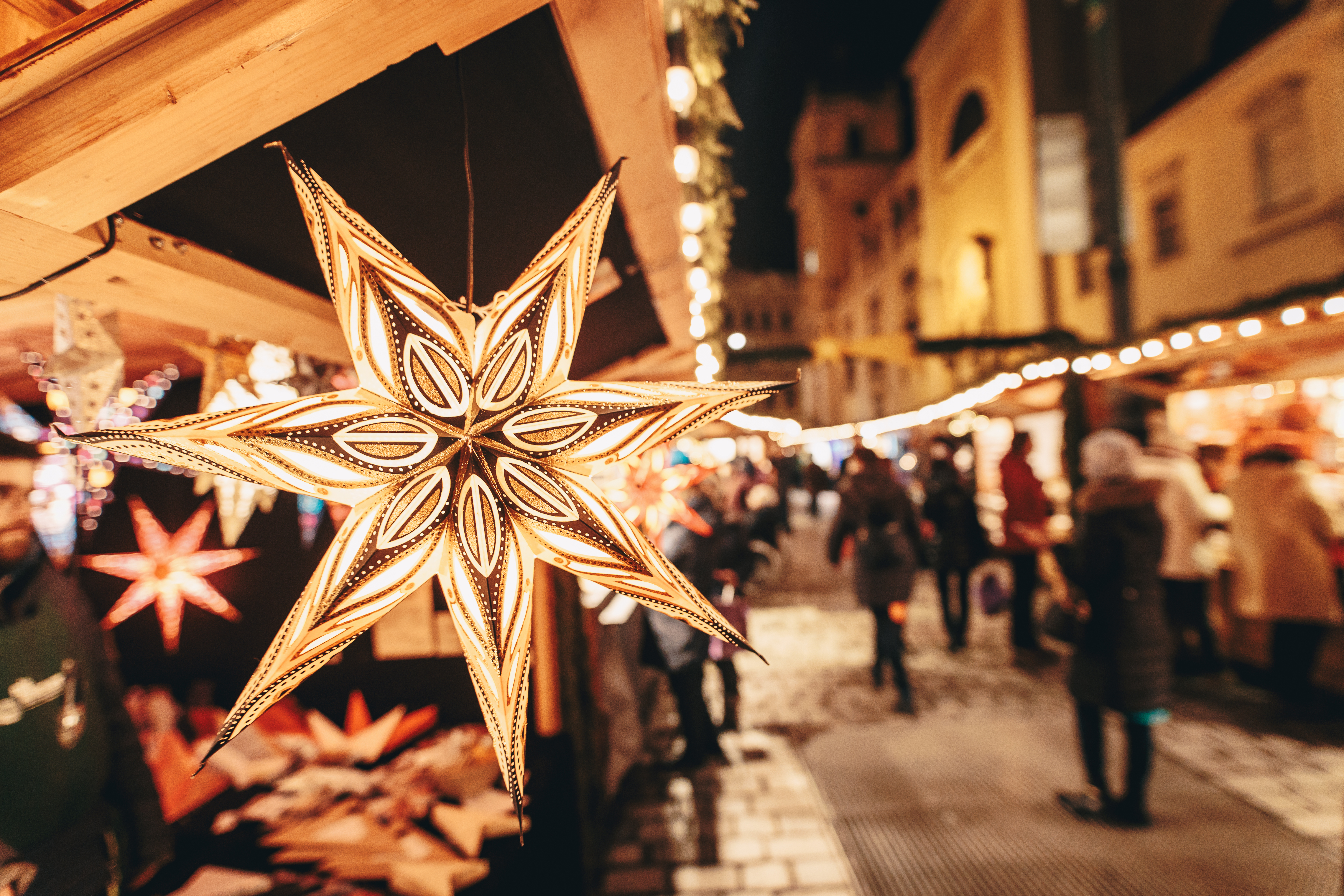 Gylden stjerne på adventmarked i Wien med varmt lys og julehandlende