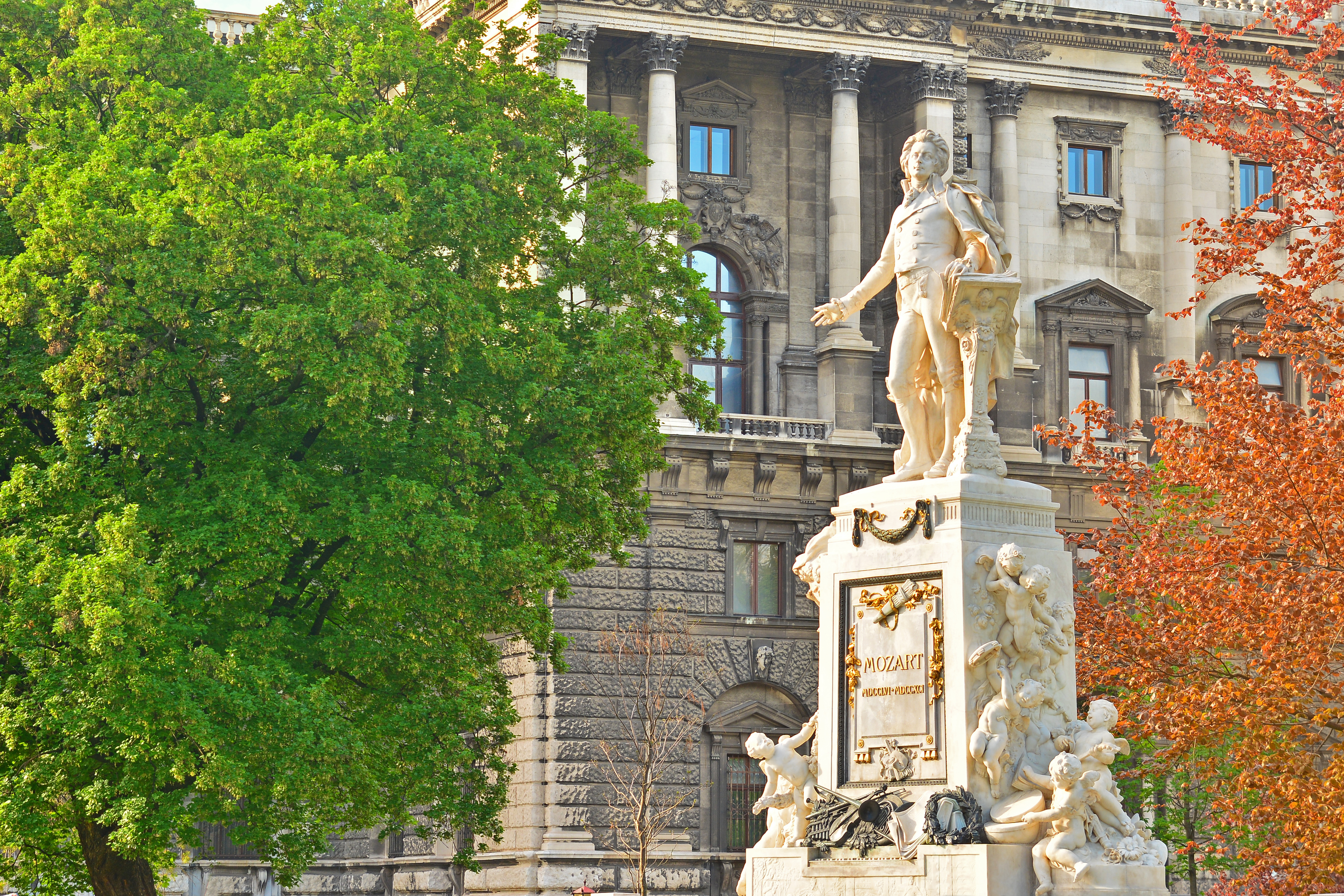 Mozart mindesmærke i Wien Burggarten med det majestætiske Hofburg Palads